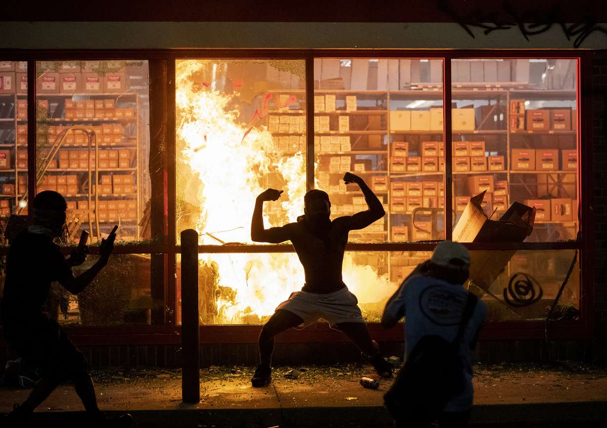 A man poses for photos in front of a fire at an AutoZone store, while protesters hold a rally for George Floyd in Minneapolis on Wednesday, May 27, 2020. (Photo: Carlos Gonzalez/Star Tribune via AP)