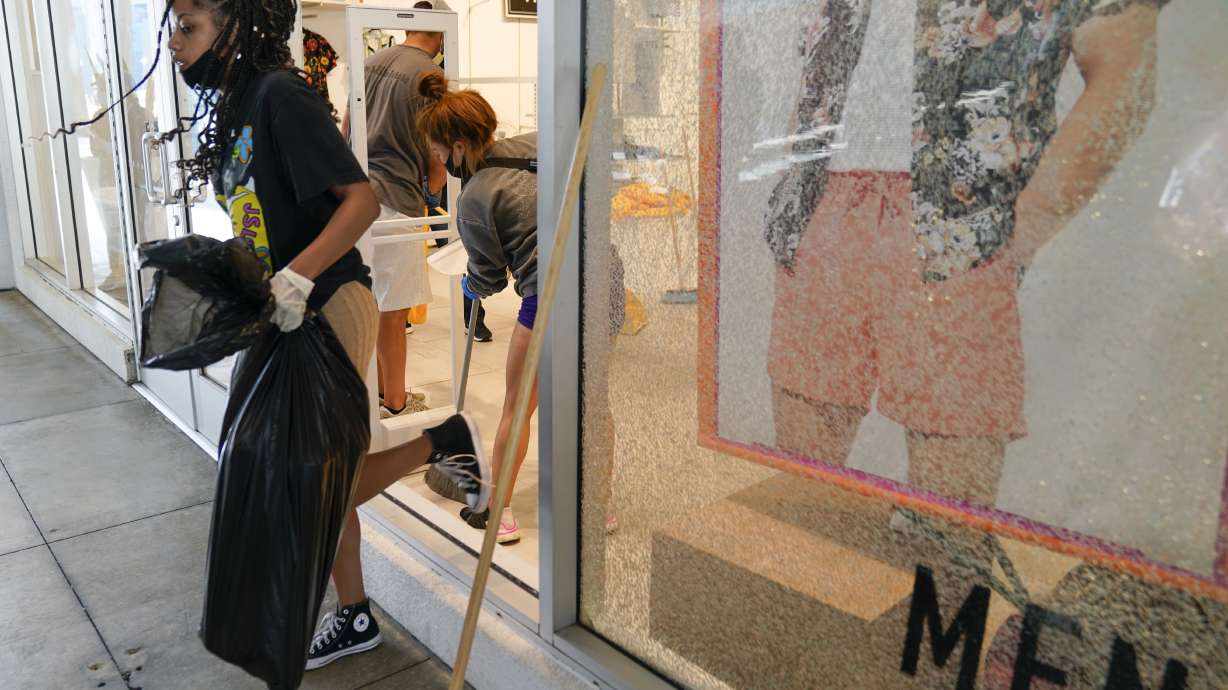 Brooms in hand, people patch up stores damaged in protests