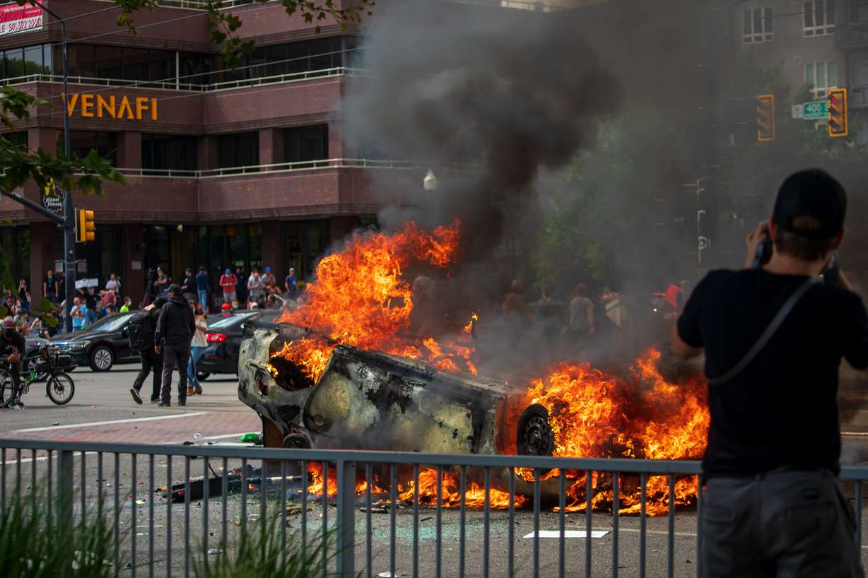 A person takes a photo of a burning Salt Lake City police car as people march along 200 East to protest the death of George Floyd by a Minnesota police officer on Saturday, May 30, 2020. The protest started peaceful but turned into a riot as the day went on. (Photo: Carter Williams, KSL.com, File)