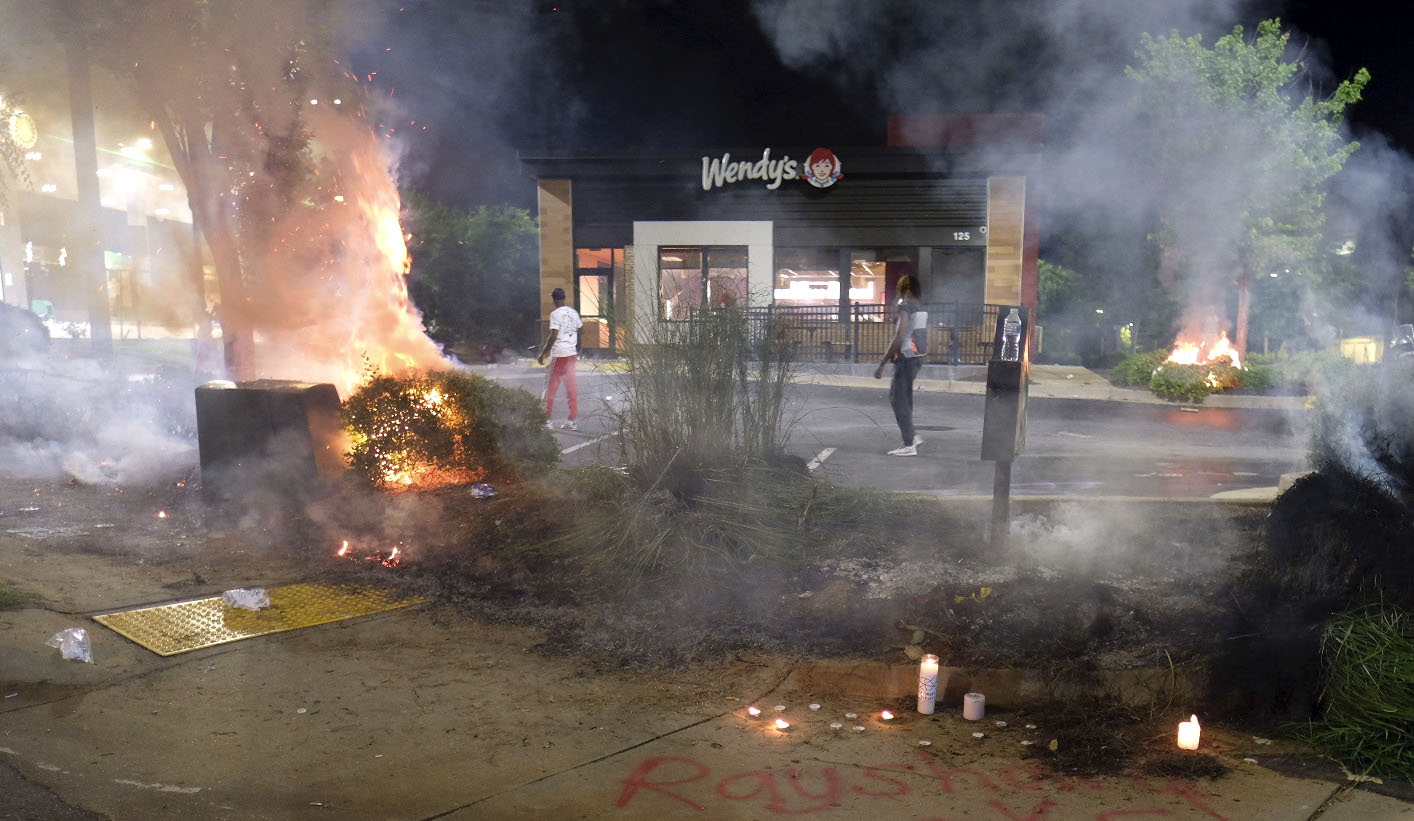 A Wendy's restaurant, background, burns Saturday, June 13, 2020, in Atlanta after demonstrators allegedly set it on fire.(Ben Gray, Atlanta Journal-Constitution via AP)
