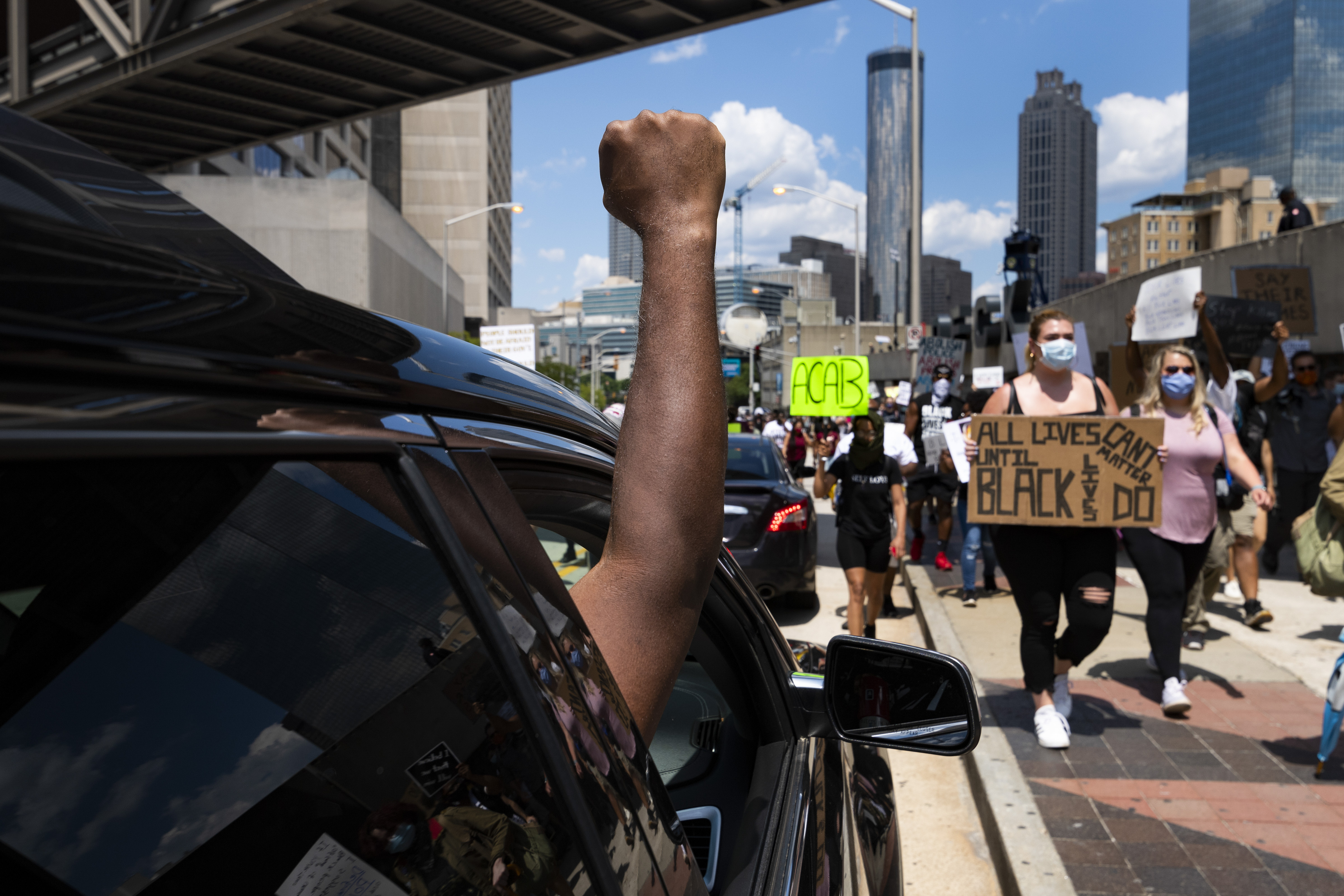 Protesters get support from a passengers of a cars they march past CNN during a demonstration over the death of Floyd, Saturday, June 13, 2020 in Atlanta. (John Amis, Atlanta Journal-Constitution via AP)
