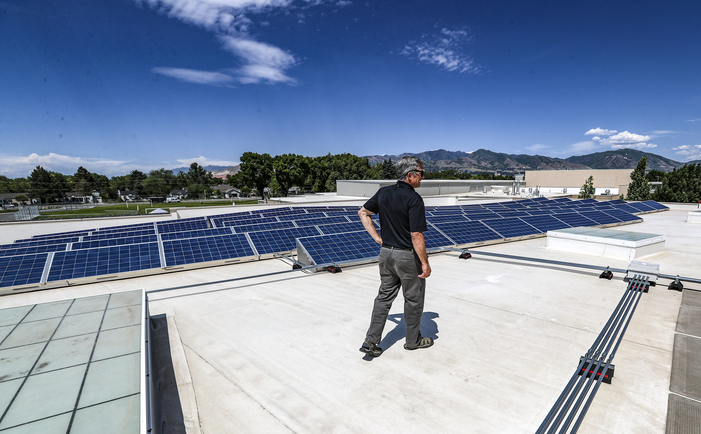 Greg Libecci, energy and resource manager for the Salt Lake City School District, stands with solar panels on the roof of Mountain View Elementary School in Salt Lake City on Wednesday, June 3, 2020. (Steve Griffin, KSL)