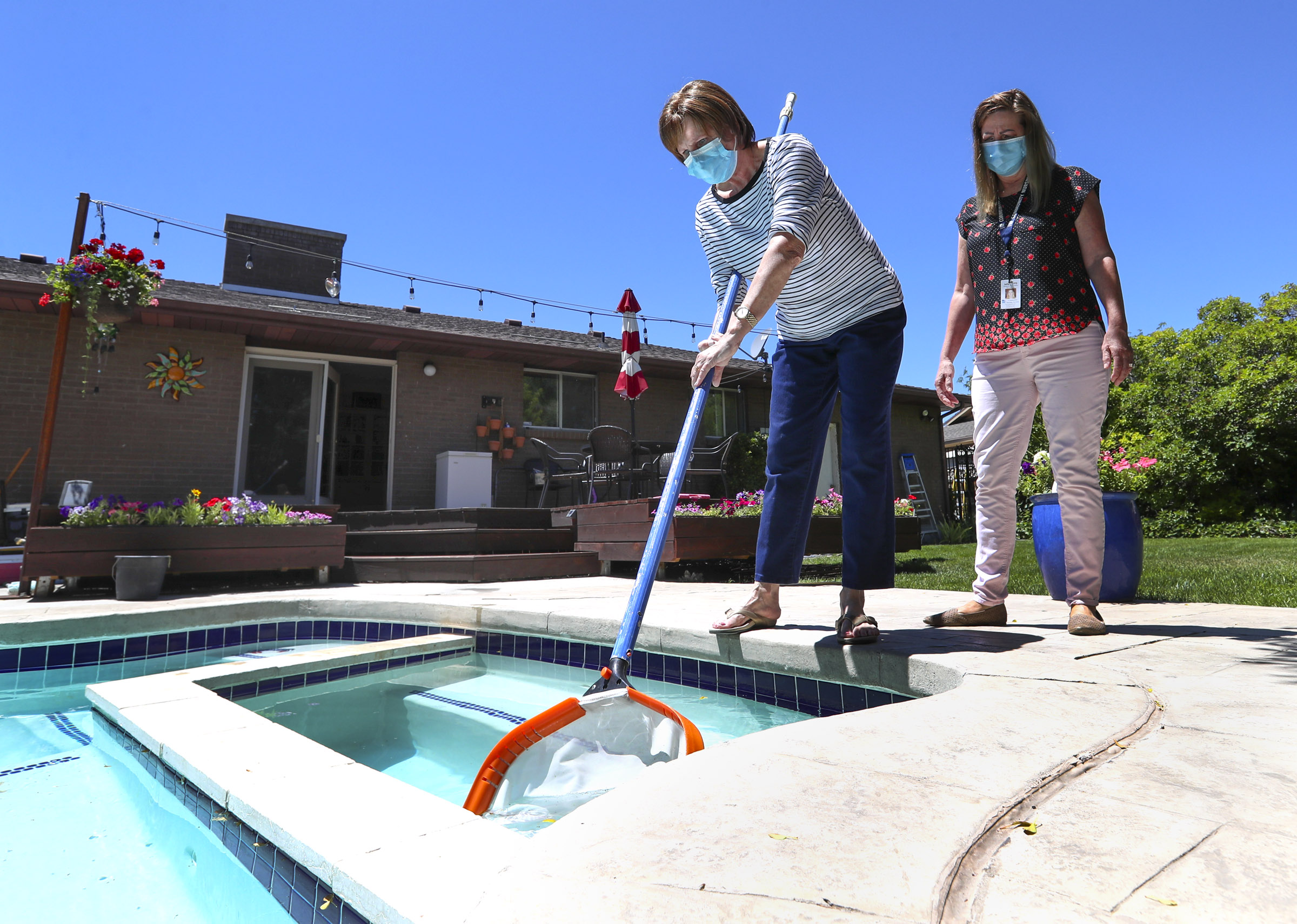 Julie Meritt, doctor of occupational therapy for Community Nursing Services, right, works with Kym Gallegos as she skims her pool at her home in Taylorsville on Friday, June 19, 2020. Community Nursing Services works with the Huntsman Cancer Institute’s Huntsman at Home Community Nursing services, which helps cancer patients stay out of the hospital by bringing treatment to their homes. (Photo: Steve Griffin, KSL)
