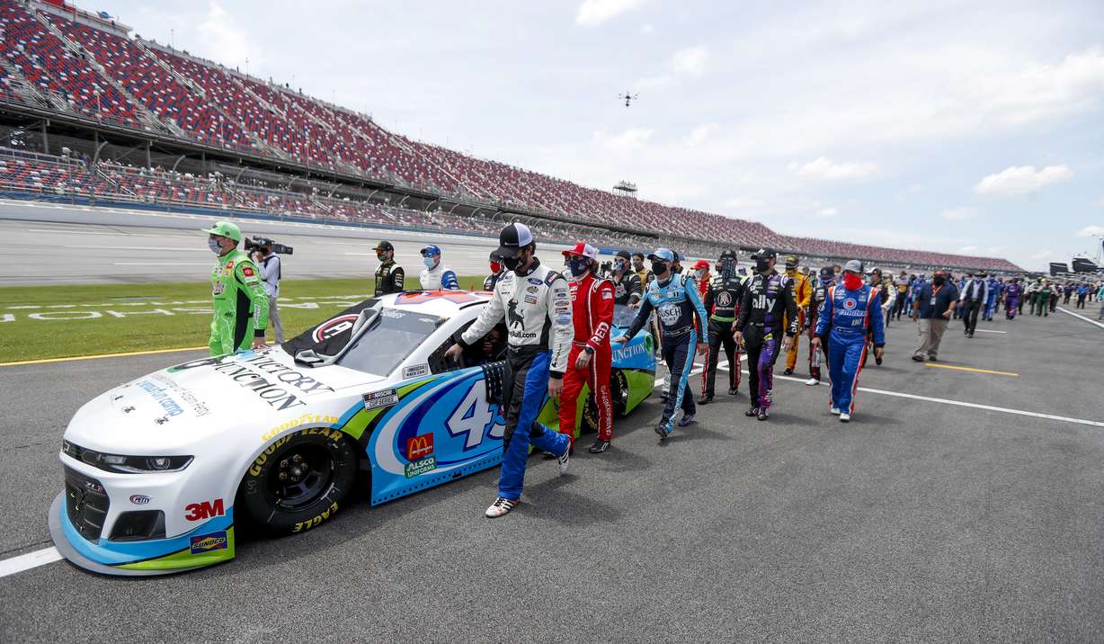 Nascar drivers Kyle Busch, left, and Corey LaJoie, right, join other drivers and crews as they push the car of Bubba Wallace to the front of the field prior to the start of the NASCAR Cup Series auto race at the Talladega Superspeedway in Talladega Ala., Monday June 22, 2020. (John Bazemore, AP Photo)