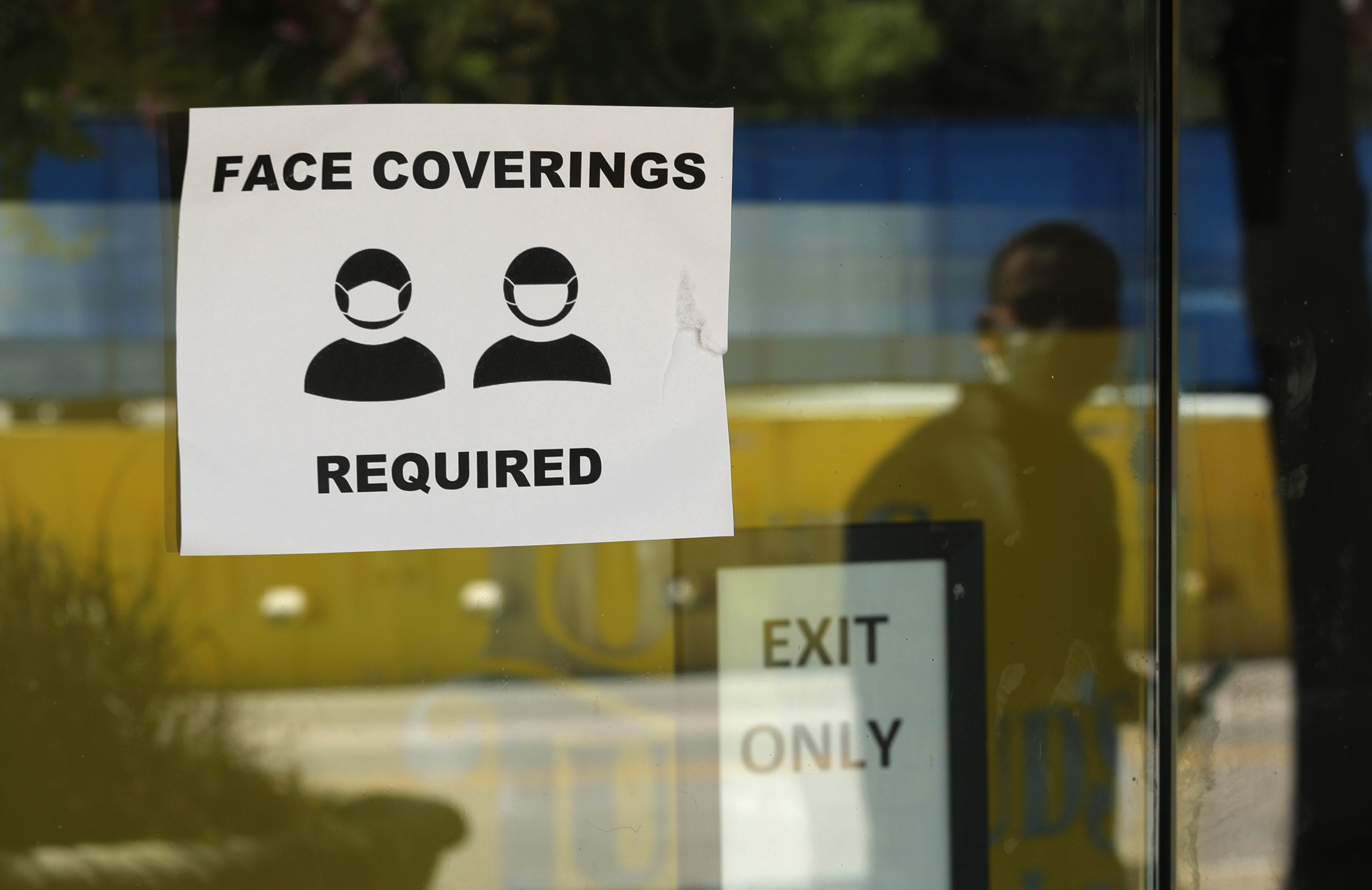 A man wearing mask to protect against the spread of COVID-19 is reflected next to a sign requiring face coverings at a business in San Antonio, Wednesday, June 24, 2020, in San Antonio. (Photo: Eric Gay, AP Photo)