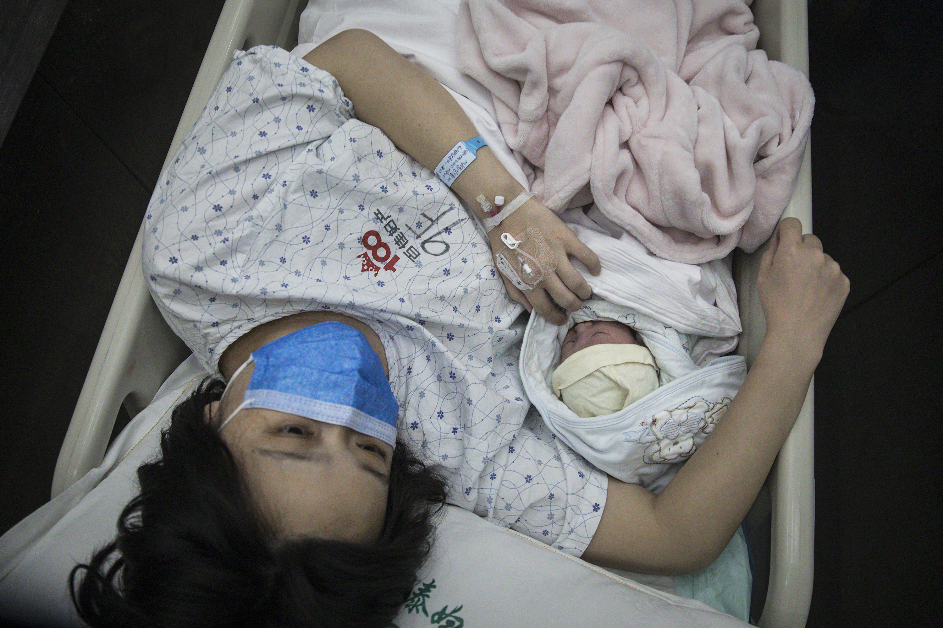A woman and her newborn baby are transferred by a nurse on February 21, 2020 in Wuhan, Hubei, China. (Stringer, Getty Images AsiaPac/Getty Images)