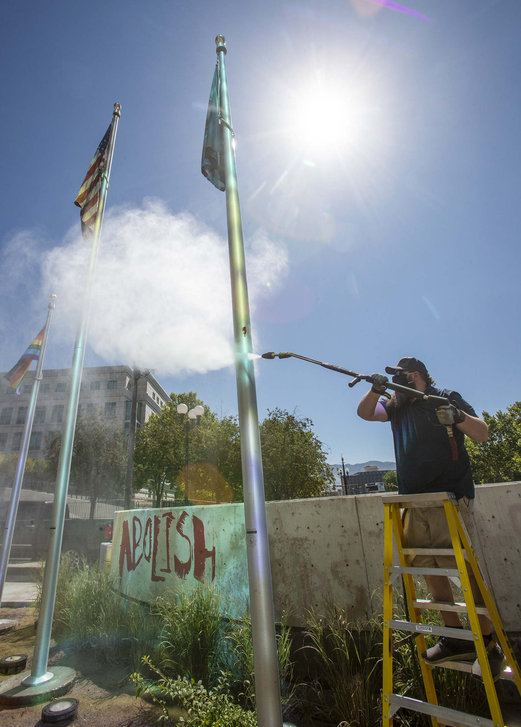 Chad Rasmussen, owner of Royce Industries, uses a pressure washer to clean paint from the flagpoles at the Salt Lake County District Attorney’s Office building in Salt Lake City on Friday, July 10, 2020. The building suffered tens of thousands of dollars in damage when protesters broke out at least three windows and spread red paint over large portions of the building and area in front of the structure on Thursday. (Photo: Scott G Winterton, KSL)