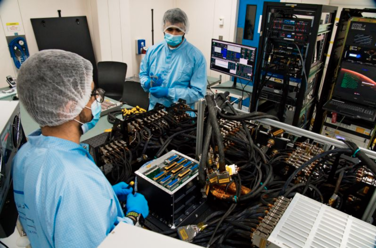 Mahmood al-Nasser, left, and Mohammad Nasser al-Emadi, center, test the Emirates Mars Mission probe's "flat sat" at the Mohammed bin Rashid Space Center in Dubai, United Arab Emirates on Thursday, June 25, 2020. (AP Photo/Jon Gambrell)