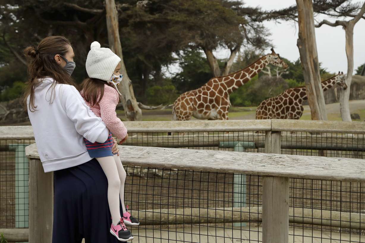 A woman holds a child while viewing giraffes at the San Francisco Zoo on Monday, July 13, 2020, in San Francisco. (Ben Margot, AP Photo)