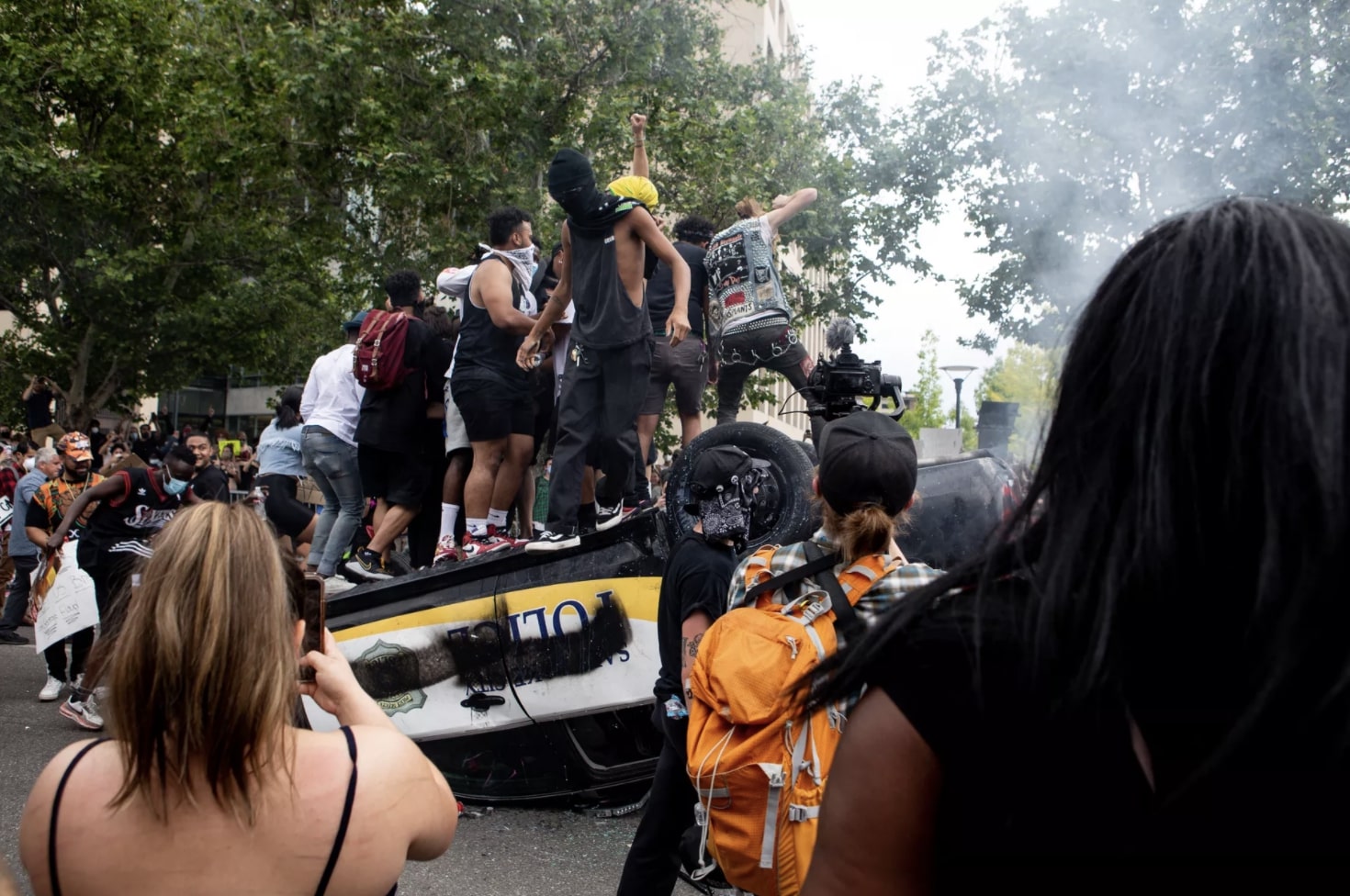 People jump on top of an overturned police car as they protest police brutality in Salt Lake City on Saturday, May 30, 2020.