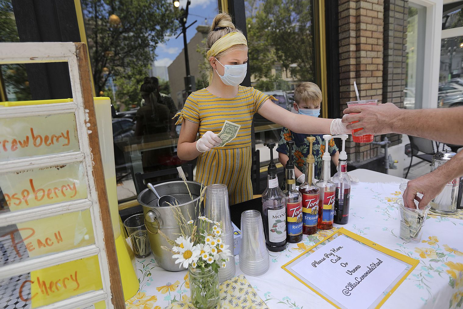 Ella Pritchard serves a customer lemonade from her lemonade stand in Provo on Tuesday, July 14, 2020. When asked how she felt about wearing a mask to school, the seventh grader said, “It wouldn’t be my favorite thing, but if we had to I wouldn’t care. It’s better than not going to school.” The Utah County Commission will hold meeting Wednesday whether to ask Gov. Gary Herbert to make a mask exemption for K-12 schools in Utah County. (Photo: Kristin Murphy, KSL)
