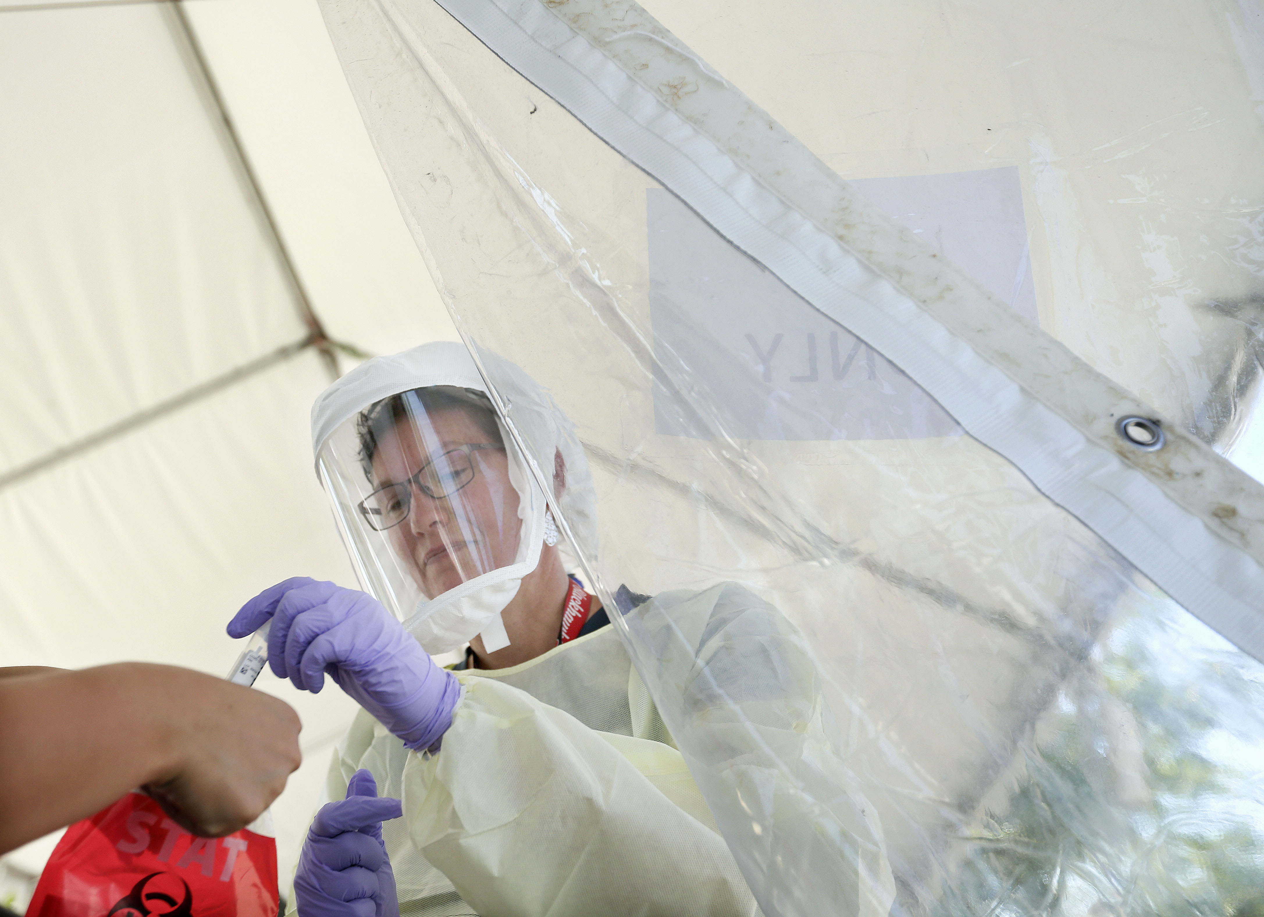 Registered nurse Heather Kessel hands a COVID-19 test to her co-worker at Intermountain Healthcare's Salt Lake Clinic on Friday, July 10, 2020. Officials from Intermountain Healthcare, University of Utah Health, MountainStar Healthcare and Steward Health Care fear that if COVID-19 cases continue to spike, they will no longer be able to effectively manage all the patients.