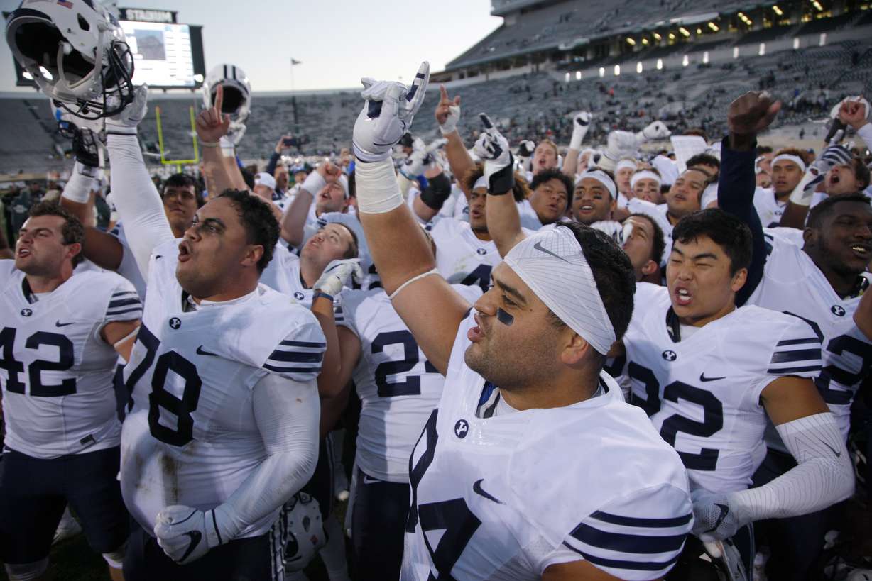 This Oct. 8, 2016, file photo shows BYU players, including Austin Heder (42), Tuni Kanuch (78), Kesni Tausinga (94) and Hiva Lee, right, celebrate following a 31-14 win over Michigan State in an NCAA college football game, in East Lansing, Mich. A team can go on the road and play a Power Five conference team and earn $1 million-$2 million, often enough to keep other sports programs afloat or fund the training table or academic center. Perhaps no school faces a bigger challenge than independent BYU, which had five games fall off its schedule — Utah, Michigan State, Arizona State and Minnesota to start the season and a Nov. 28 game against Stanford.(Photo: Al Goldis, AP Photo)