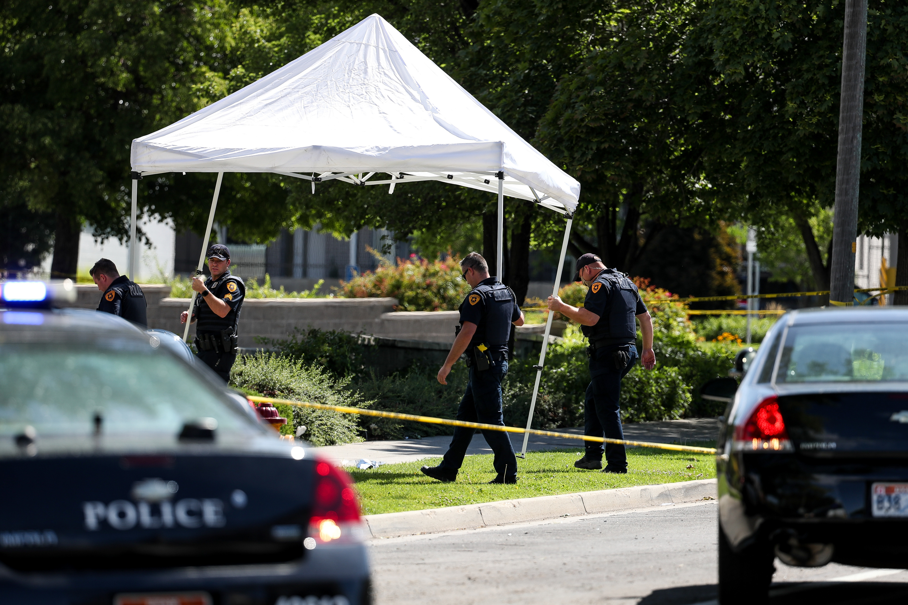 Law enforcement officers set up a shade to place over the body of a man shot and killed by Salt Lake City police officers on 500 South in Salt Lake City on Saturday, July 25, 2020. A police spokesperson said two officers responded to a call of a knife fight between two men that resulted in the officers shooting and killing one of the men.
