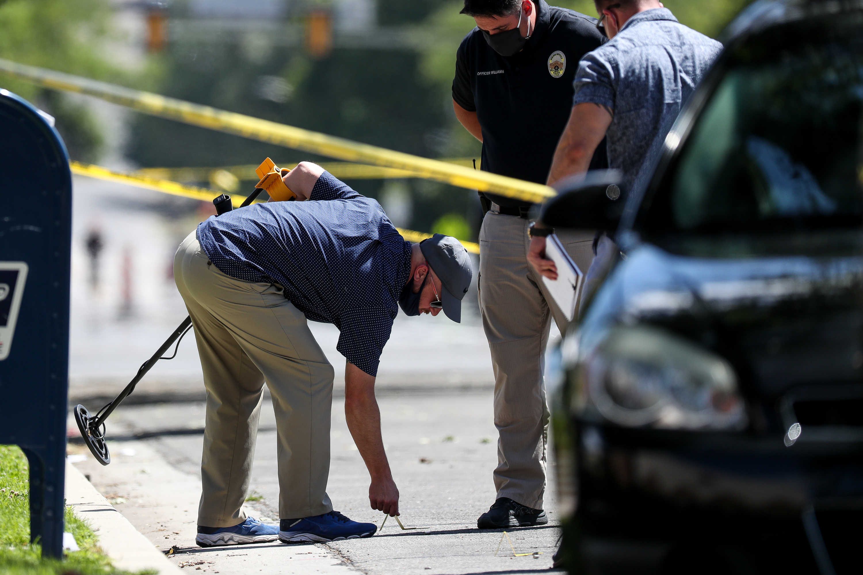 A law enforcement officer places an evidence placard next to what appears to be a shell casing after Salt Lake City police officers shot and killed a man on 500 South in Salt Lake City on Saturday, July 25, 2020.