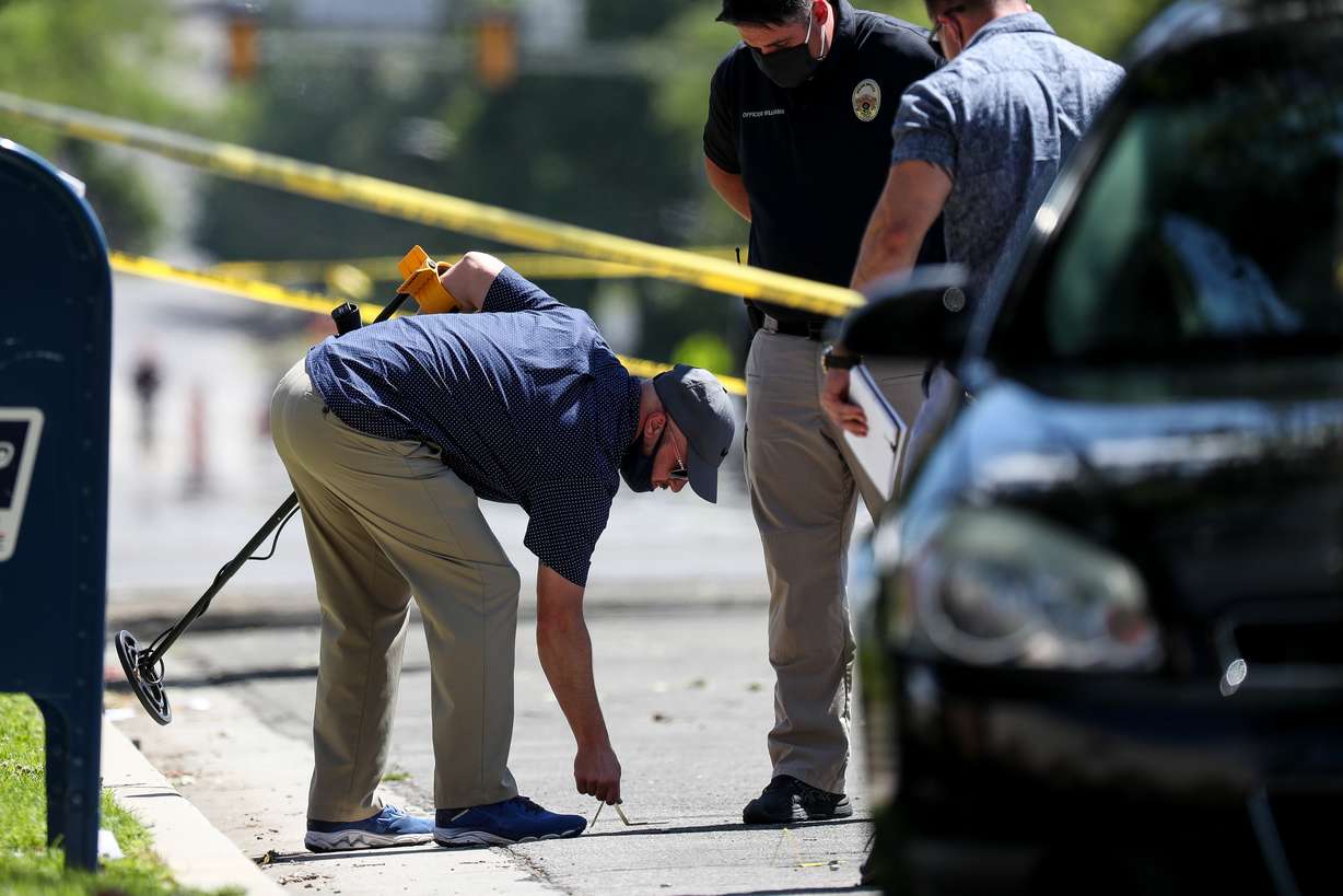 A law enforcement officer places an evidence placard next to what appears to be a shell casing after Salt Lake City police officers shot and killed a man on 500 South in Salt Lake City on Saturday, July 25, 2020.