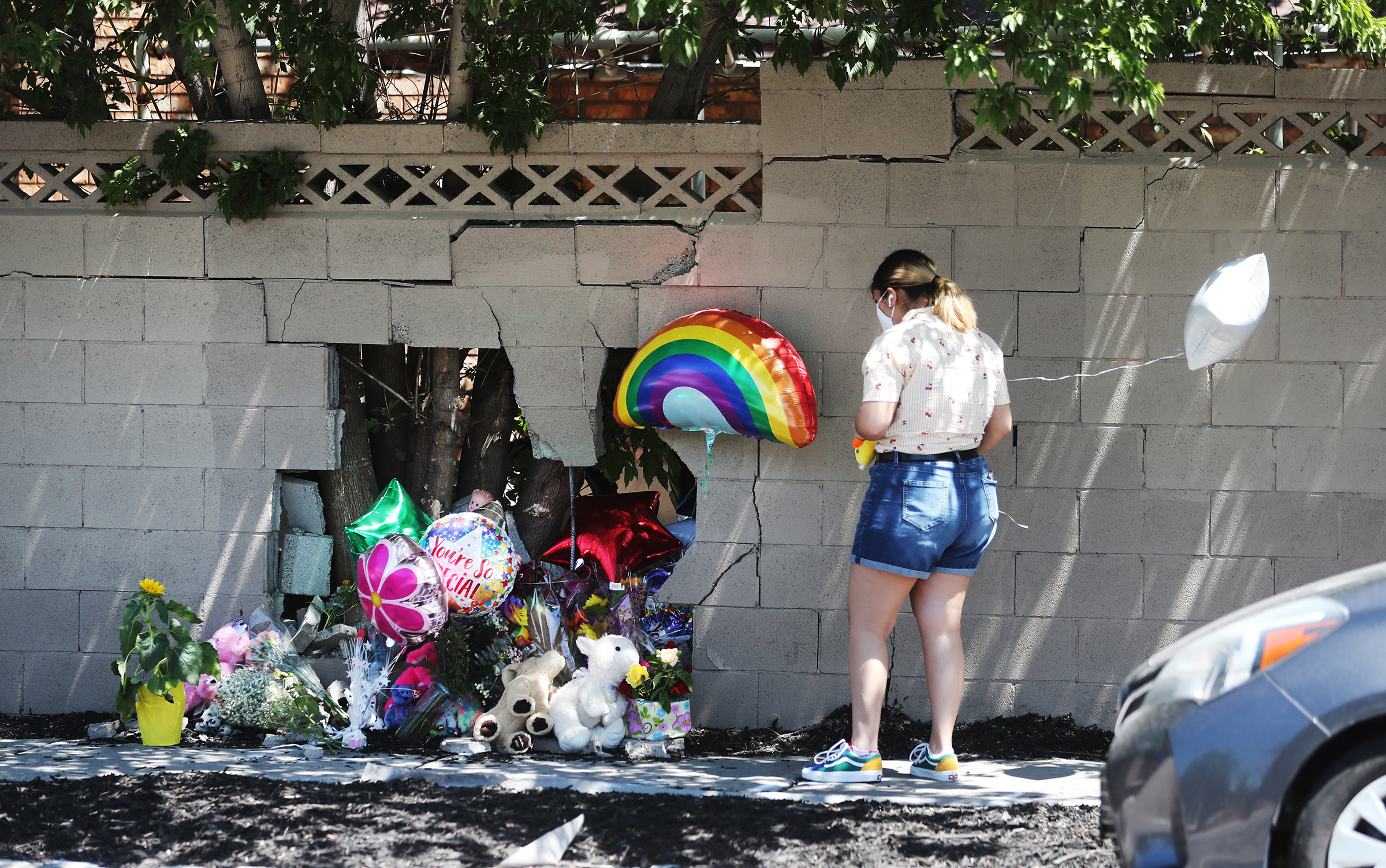 A woman places items at a small memorial at the scene of an accident in Taylorsville on Wednesday, July 29, 2020. An auto-pedestrian crash occurred Tuesday when a car stopped for a dog and was struck in the rear and pushed into a mother with a stroller, killing a 2-year-old girl.