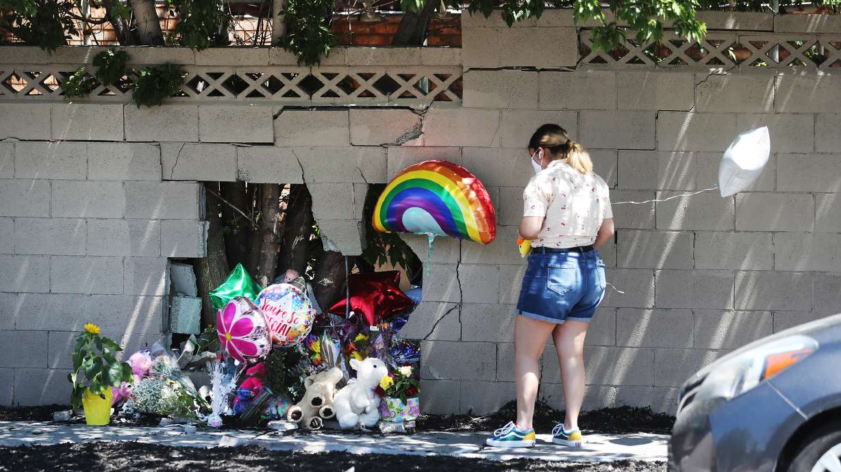 A woman places items at a small memorial at the scene of an accident in Taylorsville on Wednesday, July 29, 2020. An auto-pedestrian crash occurred Tuesday when a car stopped for a dog and was struck in the rear and pushed into a mother with a stroller, killing a 2-year-old girl.