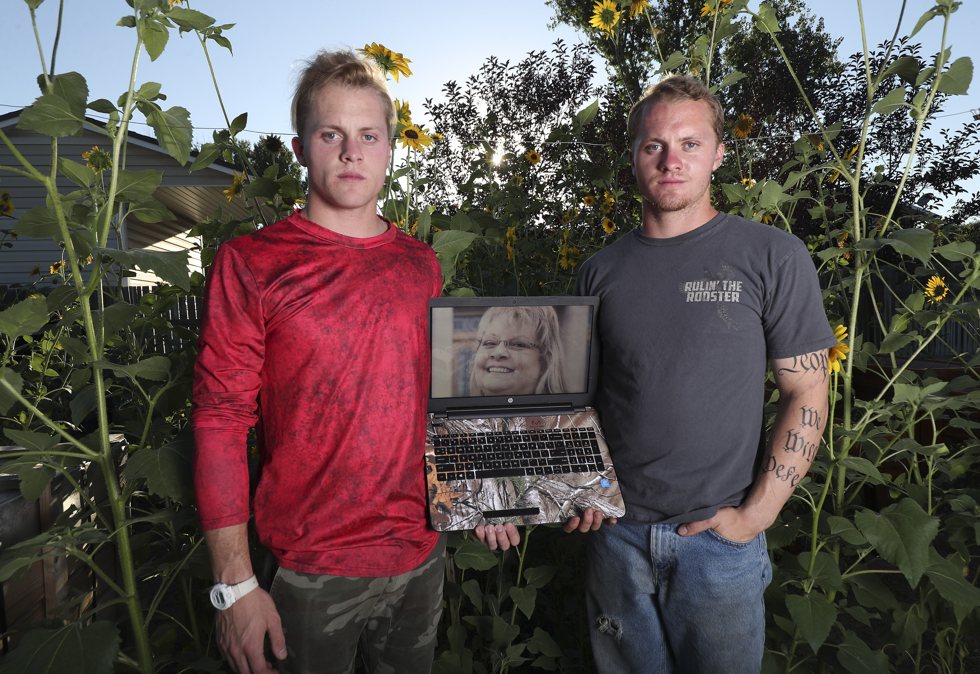 Kirwan and Everton Checketts show a photo of their mother Darla Checketts, a Ben Lomond teacher who died from complications of COVID-19 last month, at their home in West Point on Thursday, July 30, 2020. They stand near sunflowers their mother planted.