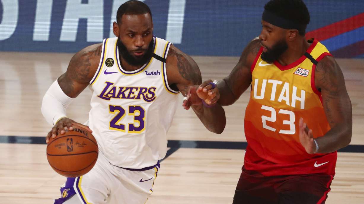 Los Angeles Lakers forward LeBron James, left, dribbles against Utah Jazz forward Royce O'Neale, right, during the first half of an NBA basketball game Monday, Aug. 3, 2020, in Lake Buena Vista, Fla.