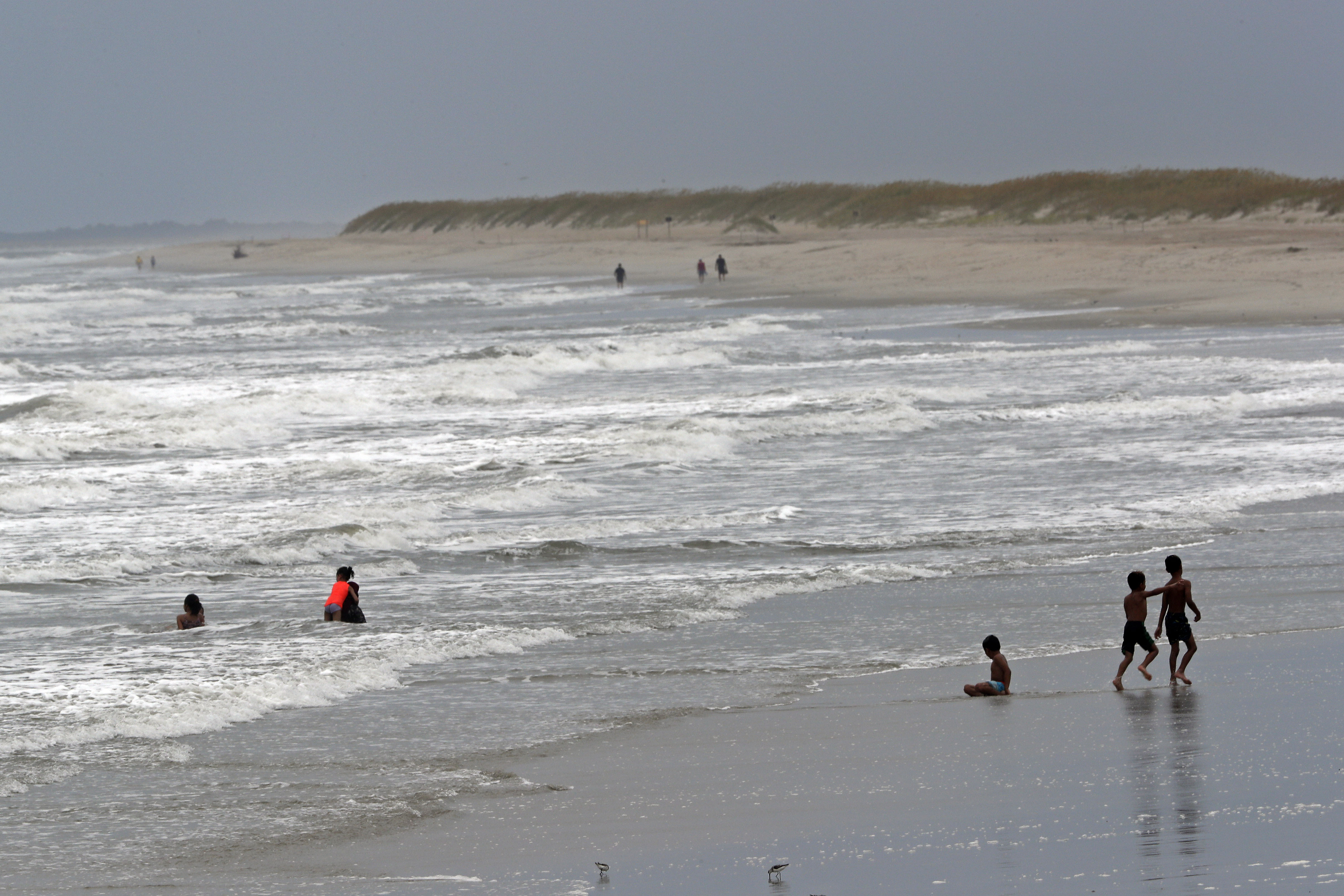 People play in the ocean as Tropical Storm Isaias approaches in Kure Beach, N.C., Monday, Aug. 3, 2020. (AP Photo/Gerry Broome)