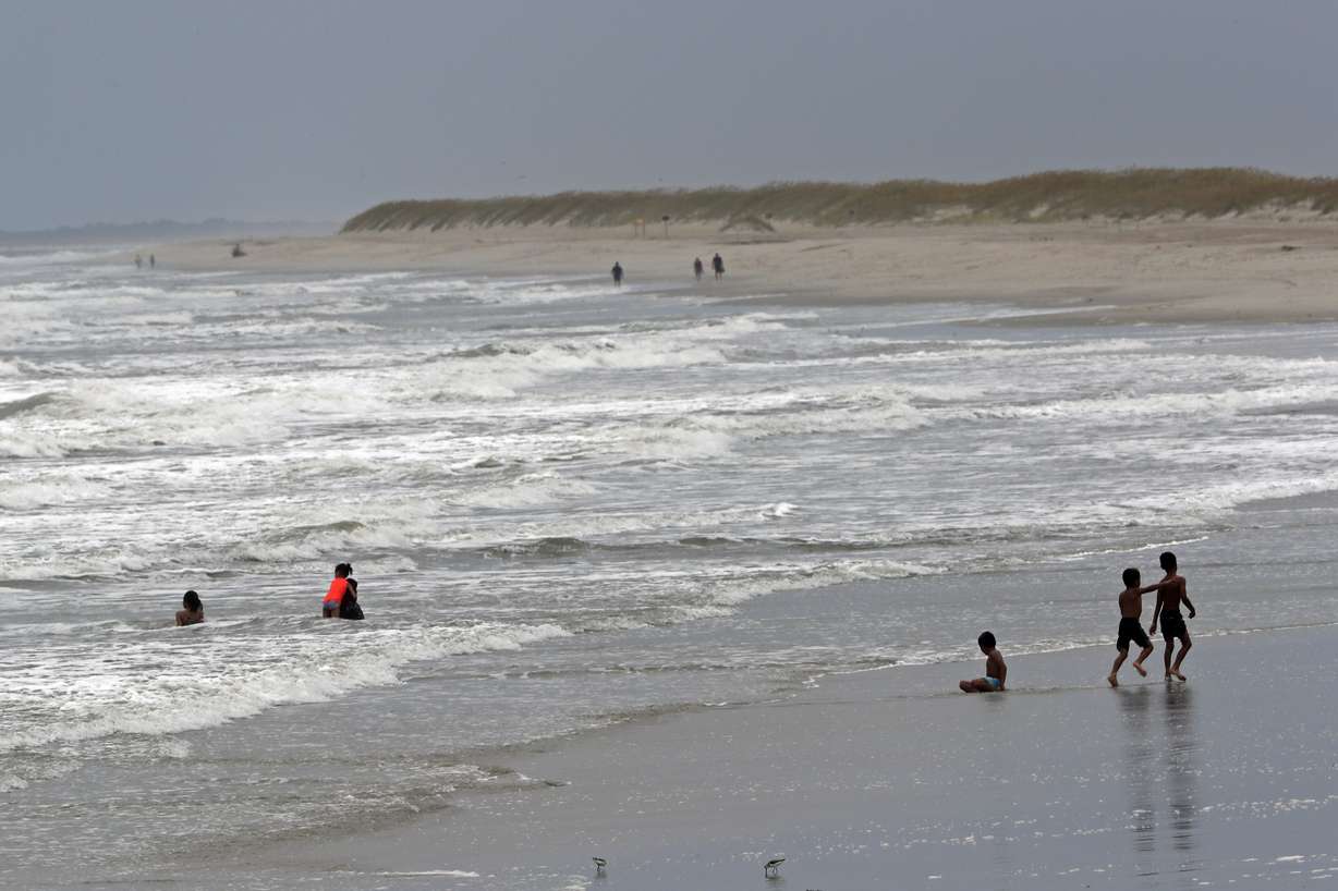People play in the ocean as Tropical Storm Isaias approaches in Kure Beach, N.C., Monday, Aug. 3, 2020. (AP Photo/Gerry Broome)