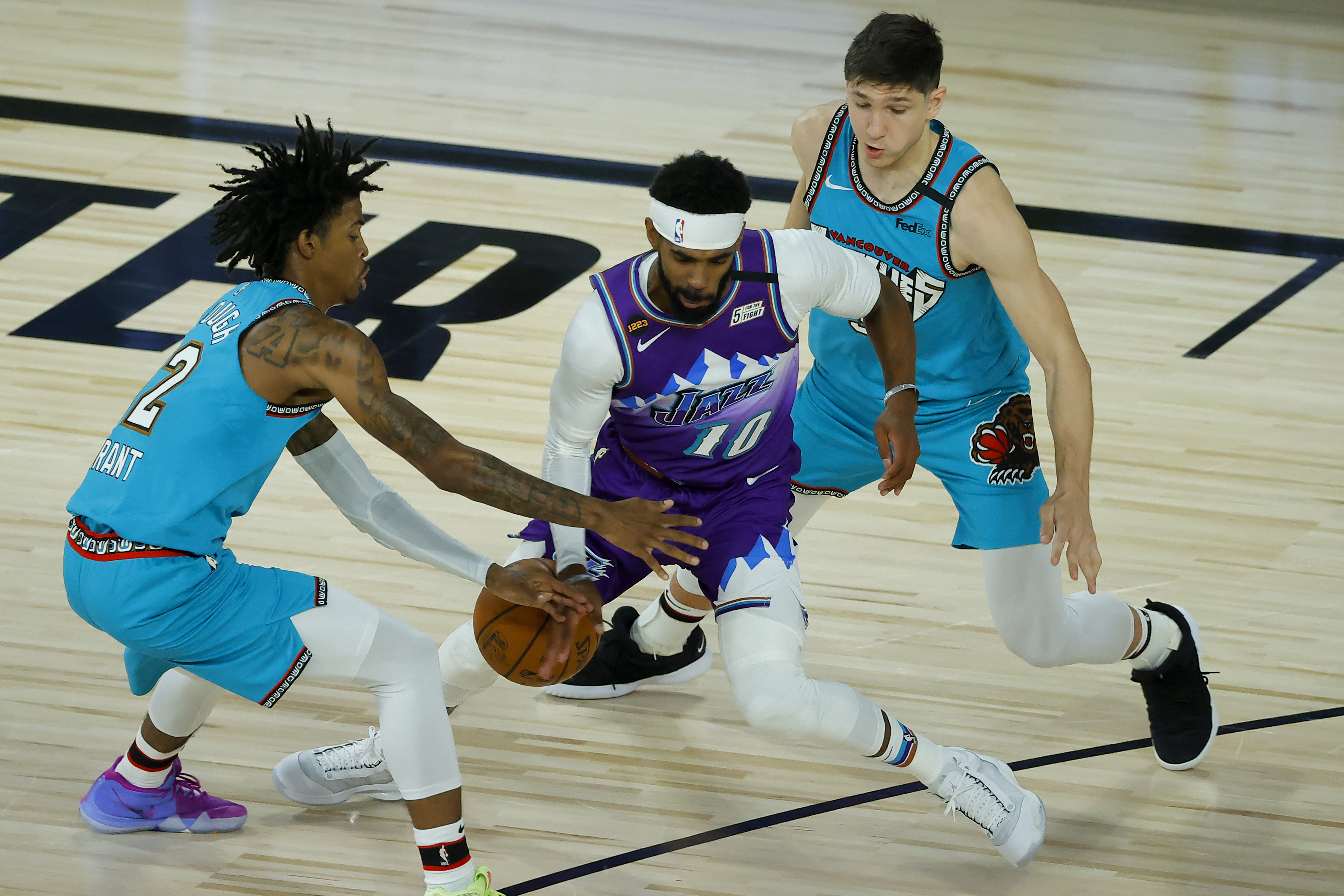 Utah Jazz's Mike Conley, center, is defended by Memphis Grizzlies' Ja Morant, left, during the first half of an NBA basketball game Wednesday, Aug. 5, 2020, in Lake Buena Vista, Fla. 

