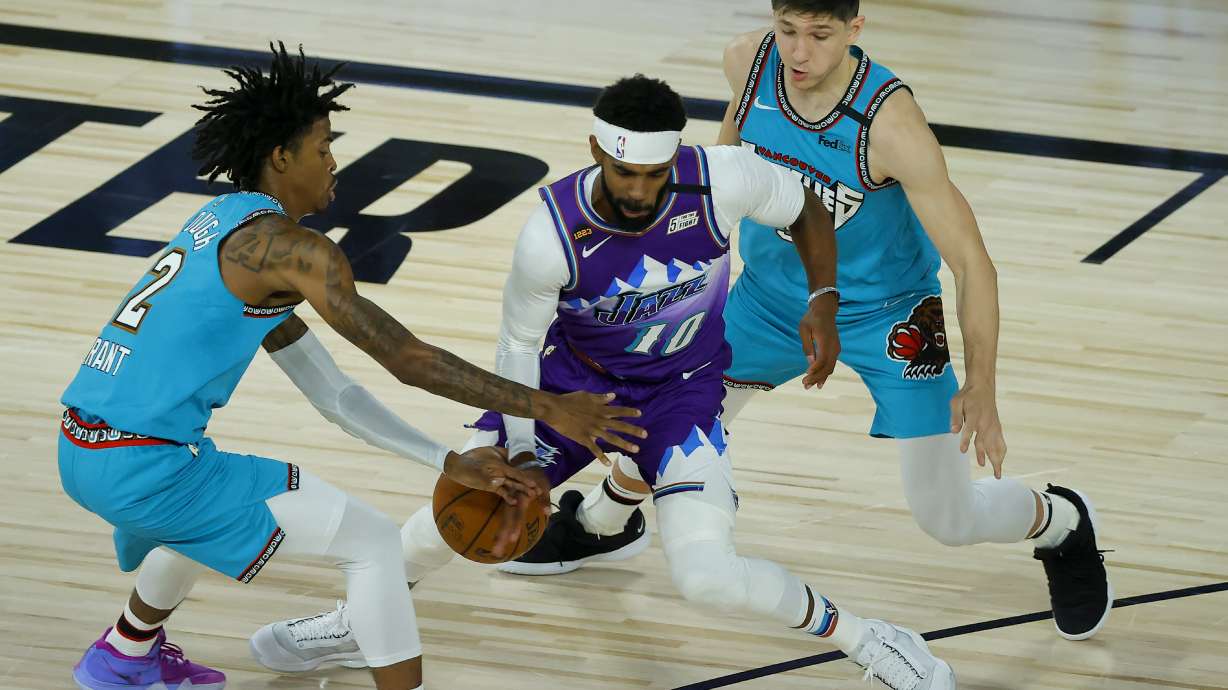 Utah Jazz's Mike Conley, center, is defended by Memphis Grizzlies' Ja Morant, left, during the first half of an NBA basketball game Wednesday, Aug. 5, 2020, in Lake Buena Vista, Fla.