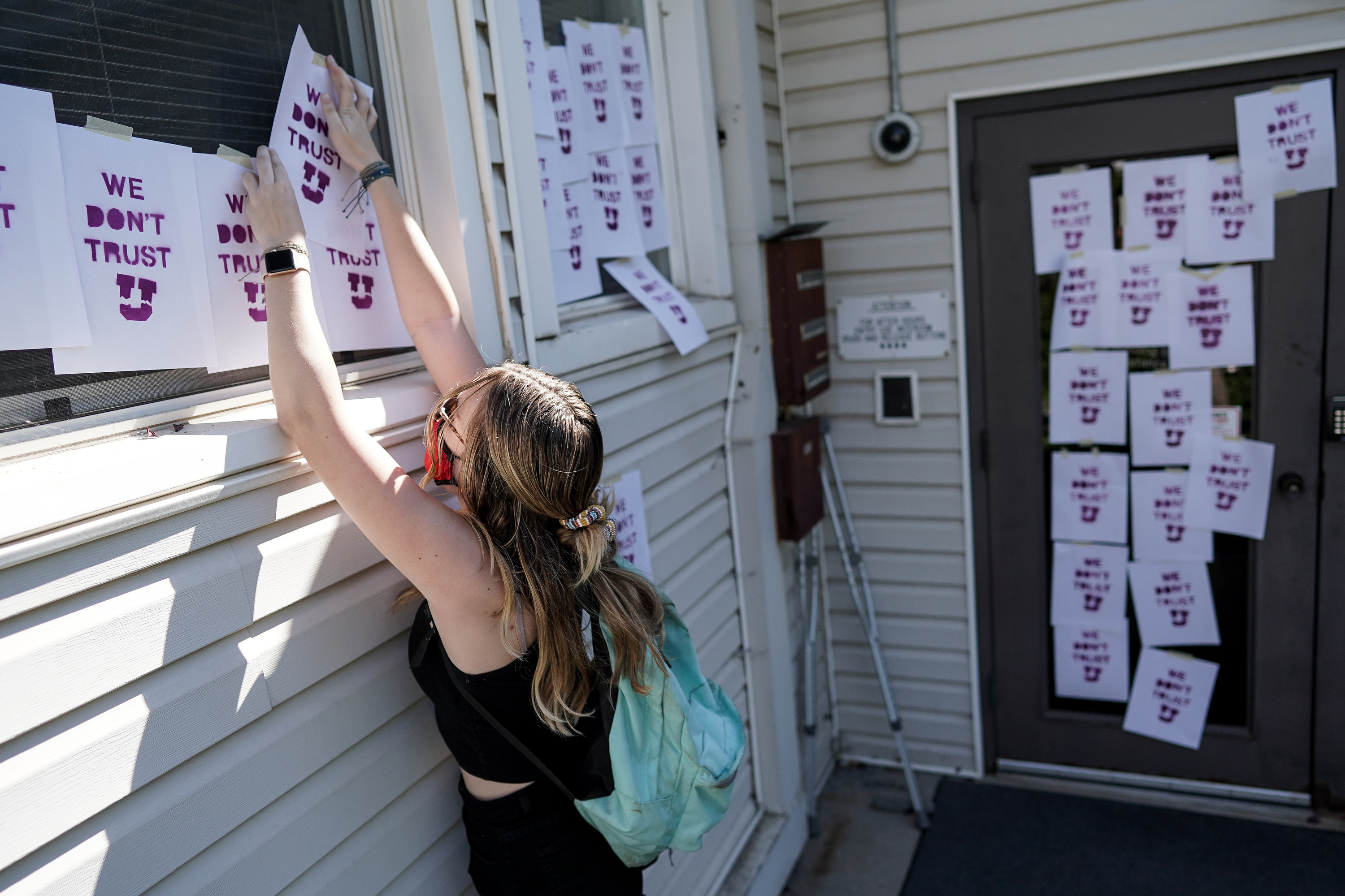 Amanda MacKay, a student and employee at the University of Utah, posts a sign on the outside of the U. Department of Public Safety building in Salt Lake City on Thursday, Aug. 6, 2020. A small group of demonstrators gathered to protest the handling of the Lauren McCluskey case amid recent reports that a police officer showed explicit photos of the slain student to fellow officers.