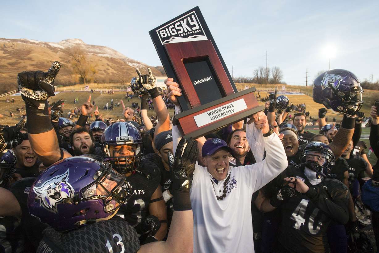 In this Nov. 18, 2017, file photo, Weber State coach Jay Hill hoists the trophy after they defeated Idaho State in an NCAA college football game for a share of the Big Sky Conference title in Ogden.