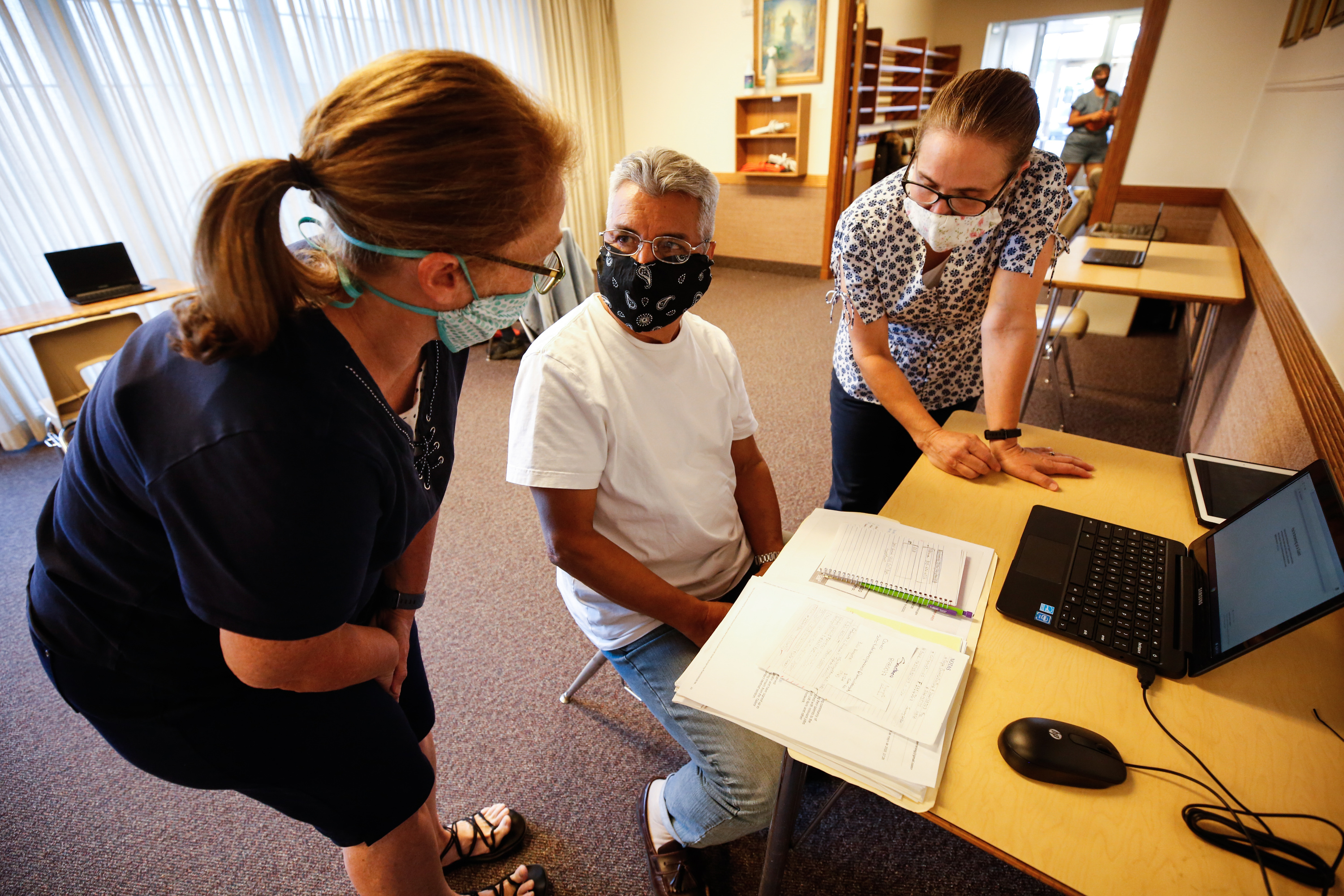 Ann Syphus, left, and Clarrisa Bartholomew, right, help Francisco Terreros use a laptop at Rose Park Stake Center of The Church of Jesus Christ of Latter-day Saints in Salt Lake City on Thursday, Aug. 6, 2020. It is part of a program for people in the community who don't have internet access in their home.