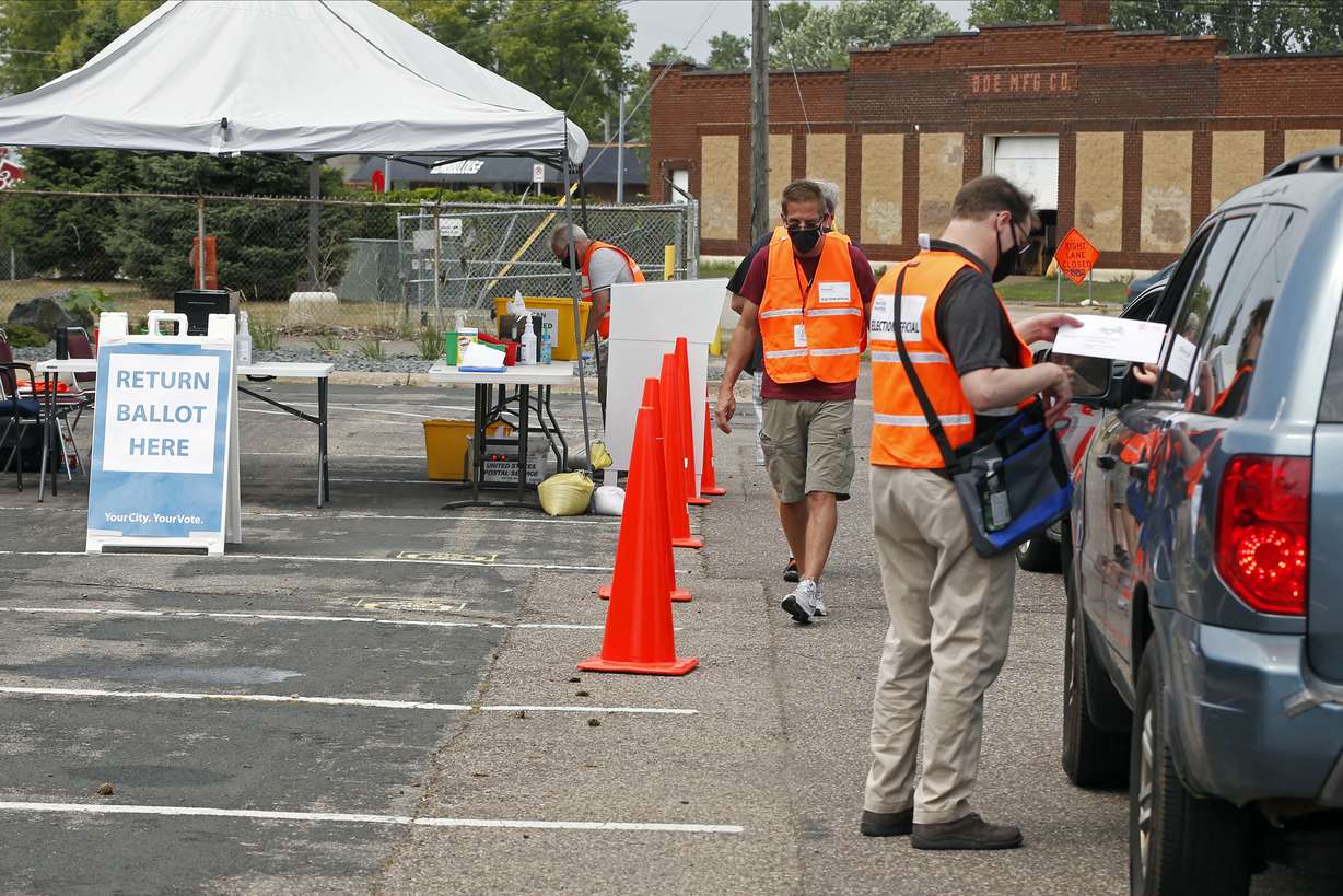 An election official inspects a ballot from a driver dropping it off Friday, Aug. 7, 2020, at an election drive-through in a parking lot at the Minneapolis Election and Voters Services headquarters in Minneapolis. Minnesota's primary election is Tuesday, Aug. 11.