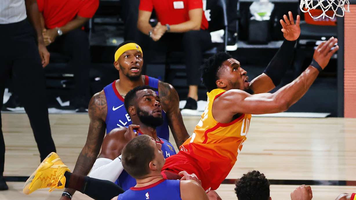 Utah Jazz' Donovan Mitchell is fouled as he goes to the basket by Denver Nuggets' Nikola Jokic (15) during the third quarter of an NBA basketball game Saturday, Aug. 8, 2020, in Lake Buena Vista, Fla.