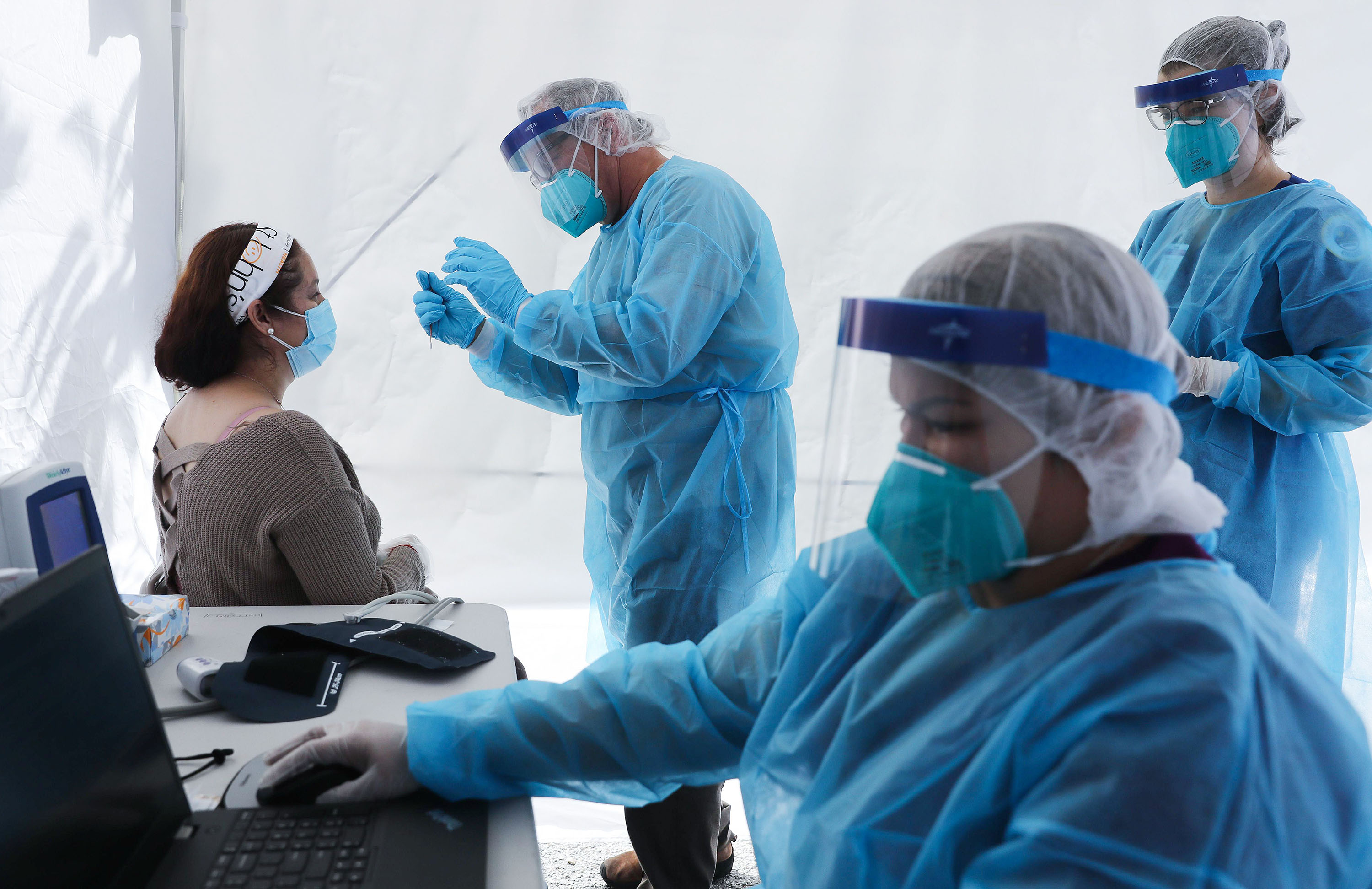 St. John's Well Child & Family Center workers prepare to test a woman for COVID-19 at a free mobile test clinic set up outside Walker Temple AME Church in South Los Angeles amid the coronavirus pandemic on July 15, 2020 in Los Angeles, California.