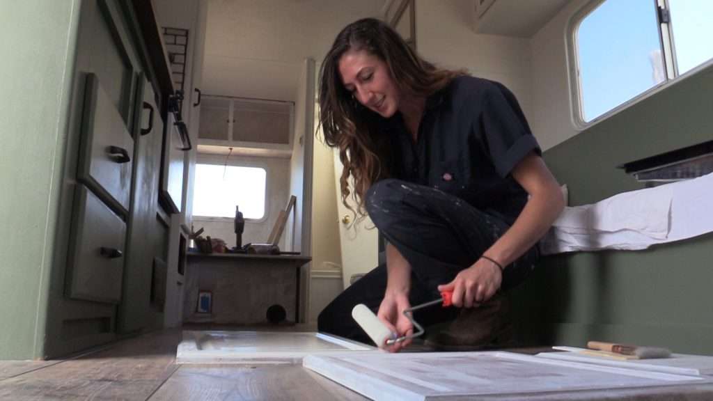 Allie Miraglia paints a cabinet door at their new home.