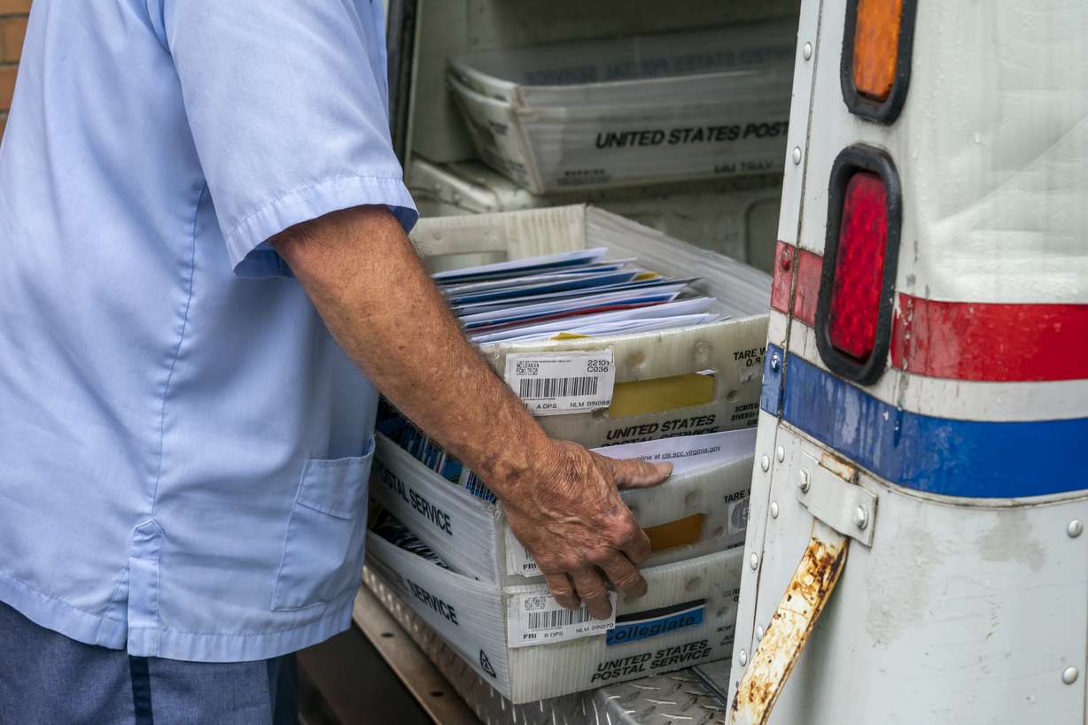 In this July 31, 2020, file photo, letter carriers load mail trucks for deliveries at a U.S. Postal Service facility in McLean, Va. The success of the 2020 presidential election could come down to a most unlikely government agency: the U.S. Postal Service.