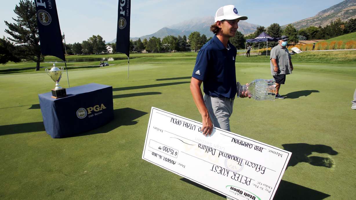 Former BYU golfer Peter Kuest walks off the 18th green with his trophy and giant check after competing in and winning the Utah Open at Riverside Country Club in Provo on Sunday, Aug. 16, 2020. Kuest shot 63, 64 and 66 for the three days.