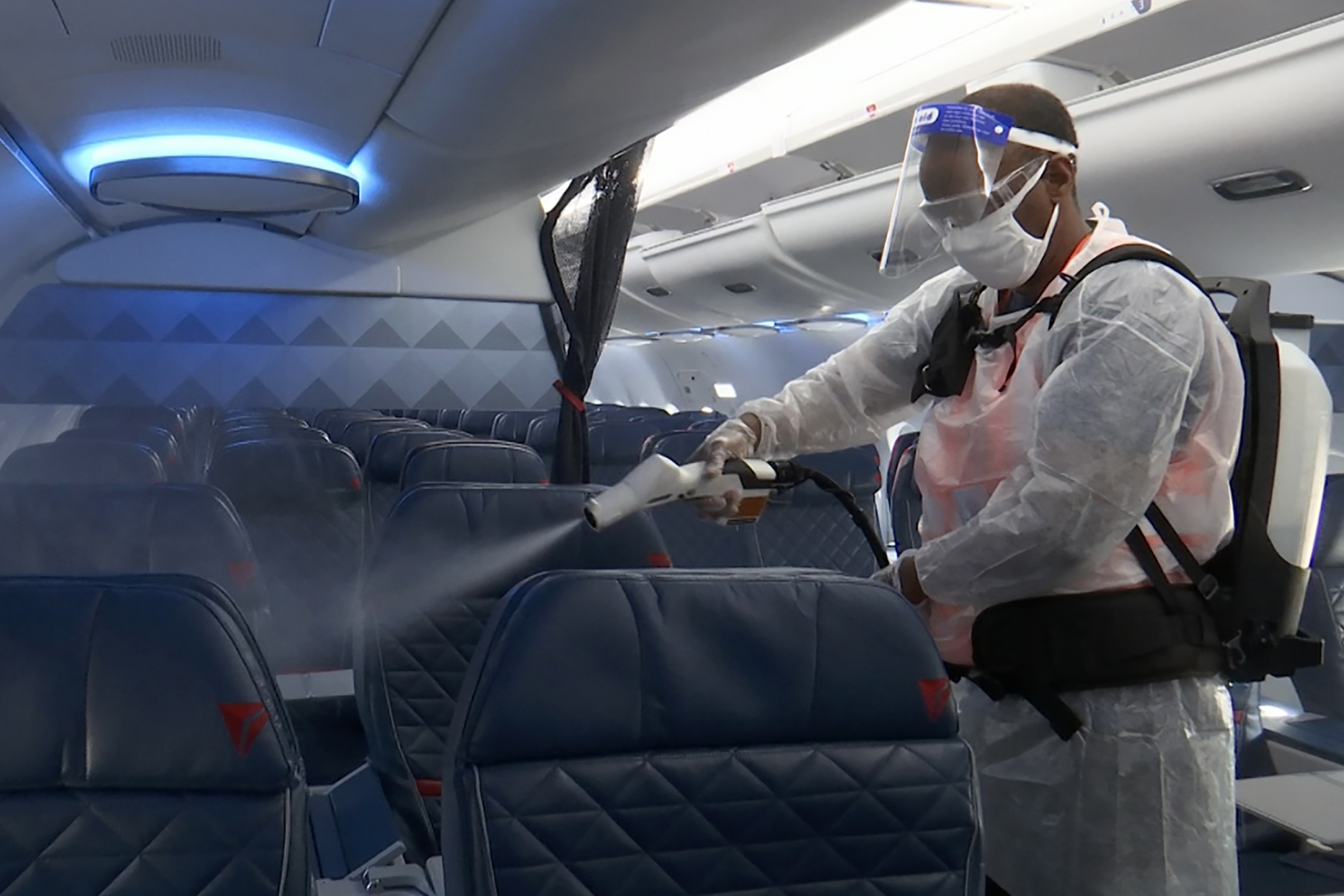 Melaku Gebermariam uses an electrostatic sprayer to disinfect the inside of a Delta Airplane between flights on July 22, at the Ronald Reagan Washington National Airport in Arlington, Va. U.S. airlines have scrambled to reassure travelers that planes are safe. They require passengers to wear face masks and are cleaning cabins more thoroughly, even spraying seats with anti-microbial mist. (AP Photo/Nathan Ellgren) [Aug-17-2020]