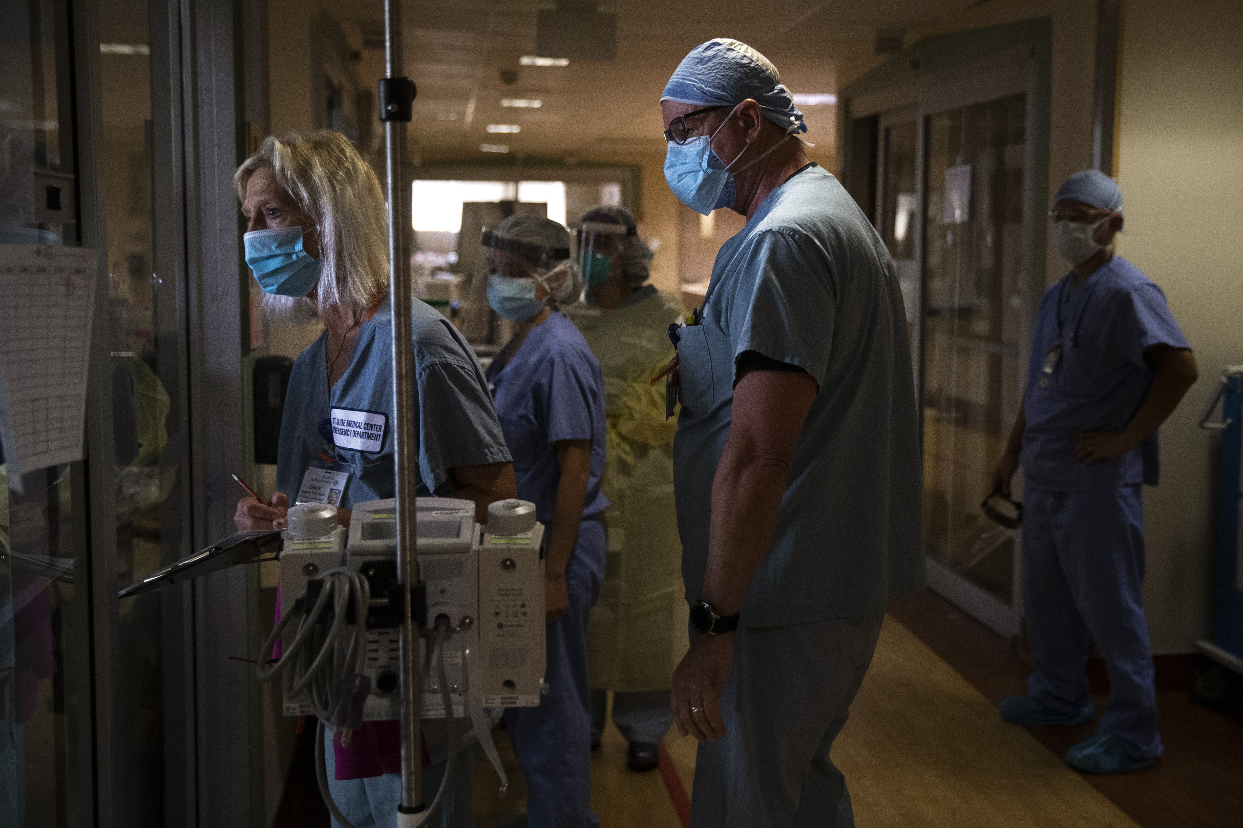 Nurse Cindy Kelbert, left, checks on a critically ill COVID-19 patient through a glass door as she is surrounded by other nurses at St. Jude Medical Center in Fullerton, Calif., Tuesday, July 7, 2020. (AP Photo/Jae C. Hong) [Aug-17-2020]