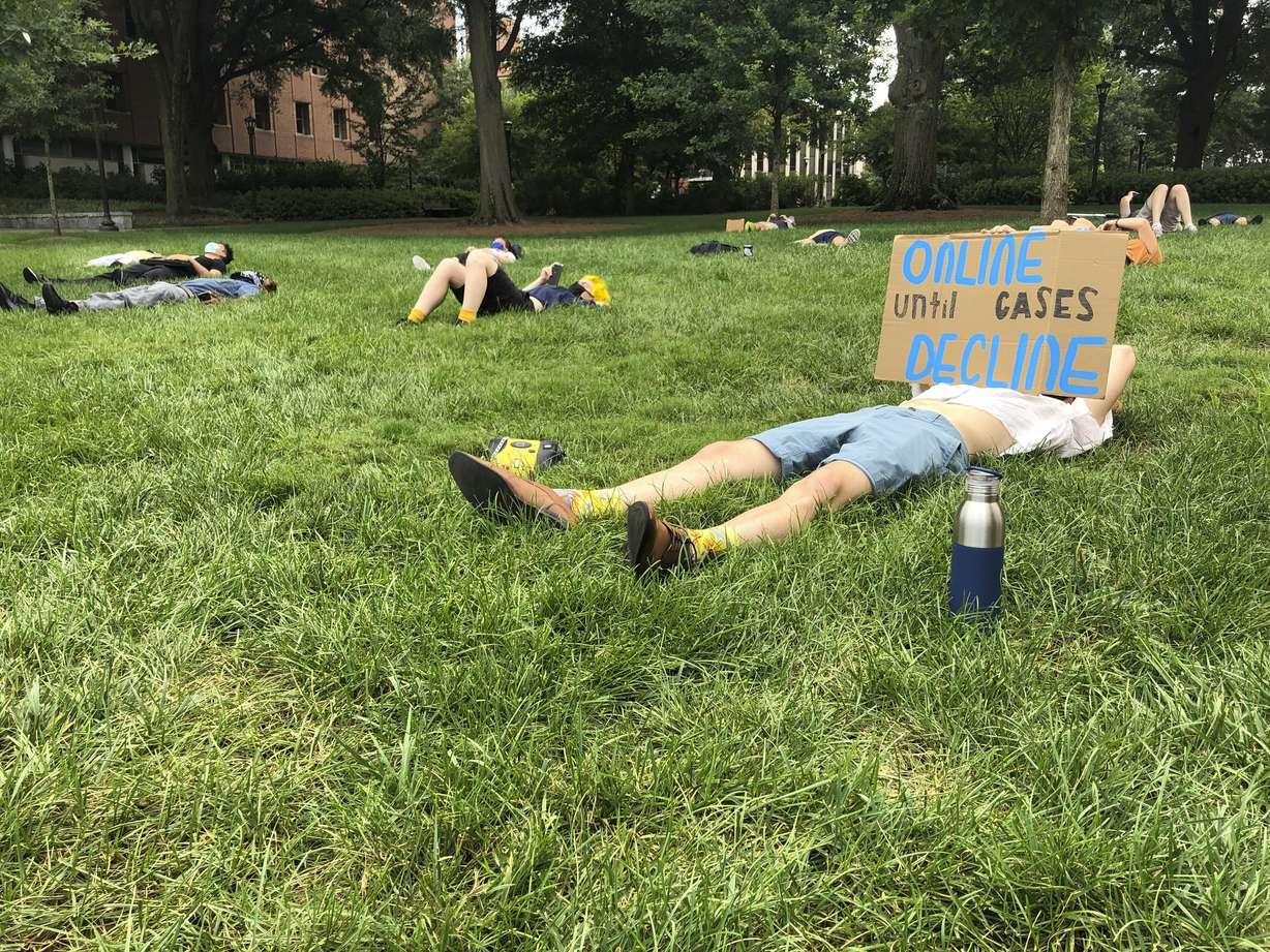 A protester holds a sign opposing in-person classes Monday, August 17, 2020, at a "die-in" at Georgia Tech in Atlanta. More of the state's public universities are opening for the fall term, trying to balance concern about COVID-19 infections against a mandate for on-campus classes citing financial needs and student desires.
