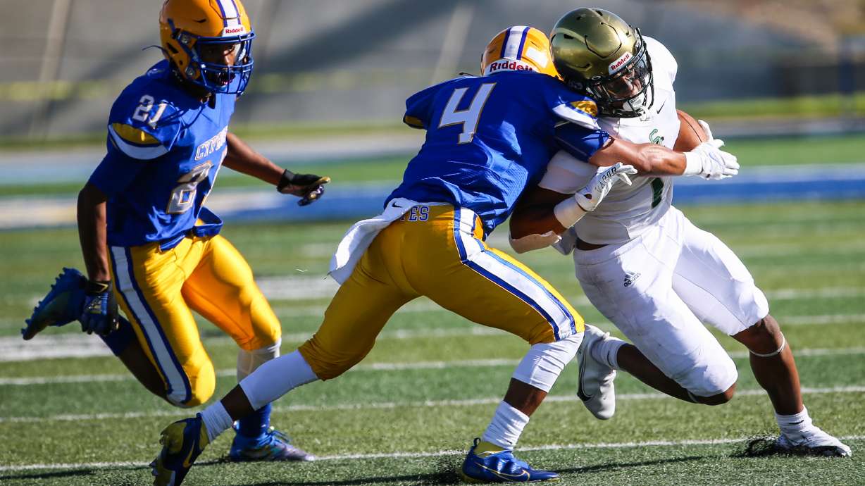 Cyprus’ Adrian Banuelos (4) attempts to stop Snow Canyon’s Bretton Stone (1) with Cary Butler (21) following behind during a high school football game at Cyprus High School in Magna on Friday, Aug. 14, 2020.