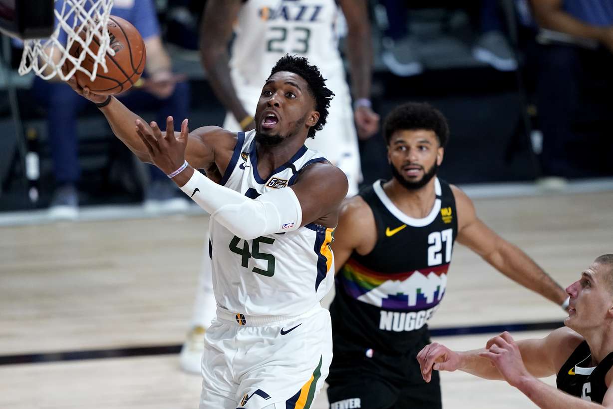 Utah Jazz's Donovan Mitchell (45) drives as Denver Nuggets' Jamal Murray (27) looks on during the first half of an NBA basketball first round playoff game, Monday, Aug. 3, 2020, in Lake Buena Vista, Fla.