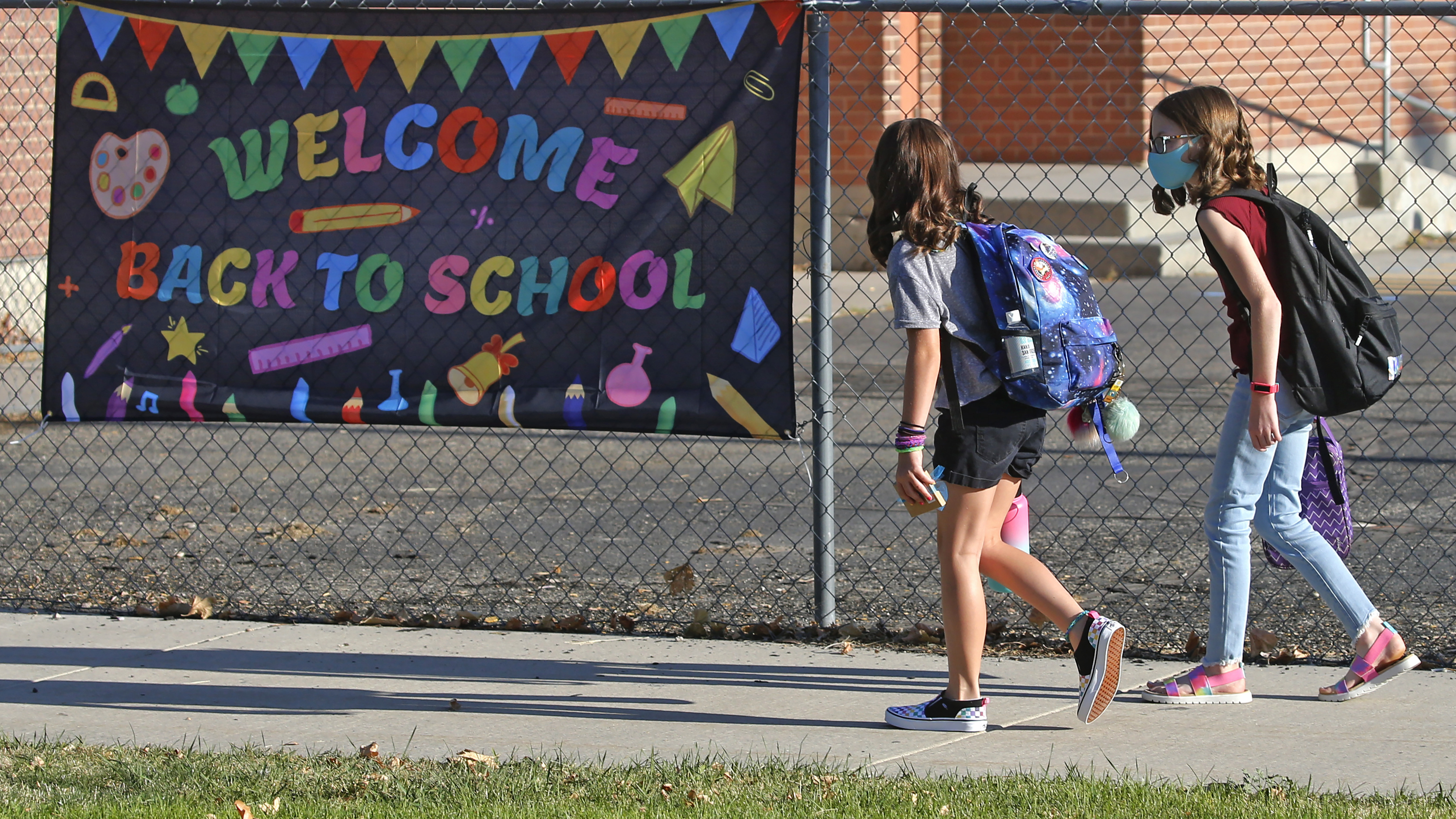FILE - In this Aug. 17, 2020, file photo, Cimmie Hunter, left, and Cadence Ludlow, both 6th graders, arrive at Liberty Elementary School during the first day of class in Murray, Utah. For countless families across the country, the school year is opening in disarray and confusion, with coronavirus outbreaks triggering sudden closings, mass quarantines and deep anxiety among parents. (AP Photo/Rick Bowmer, File) [Aug-21-2020]