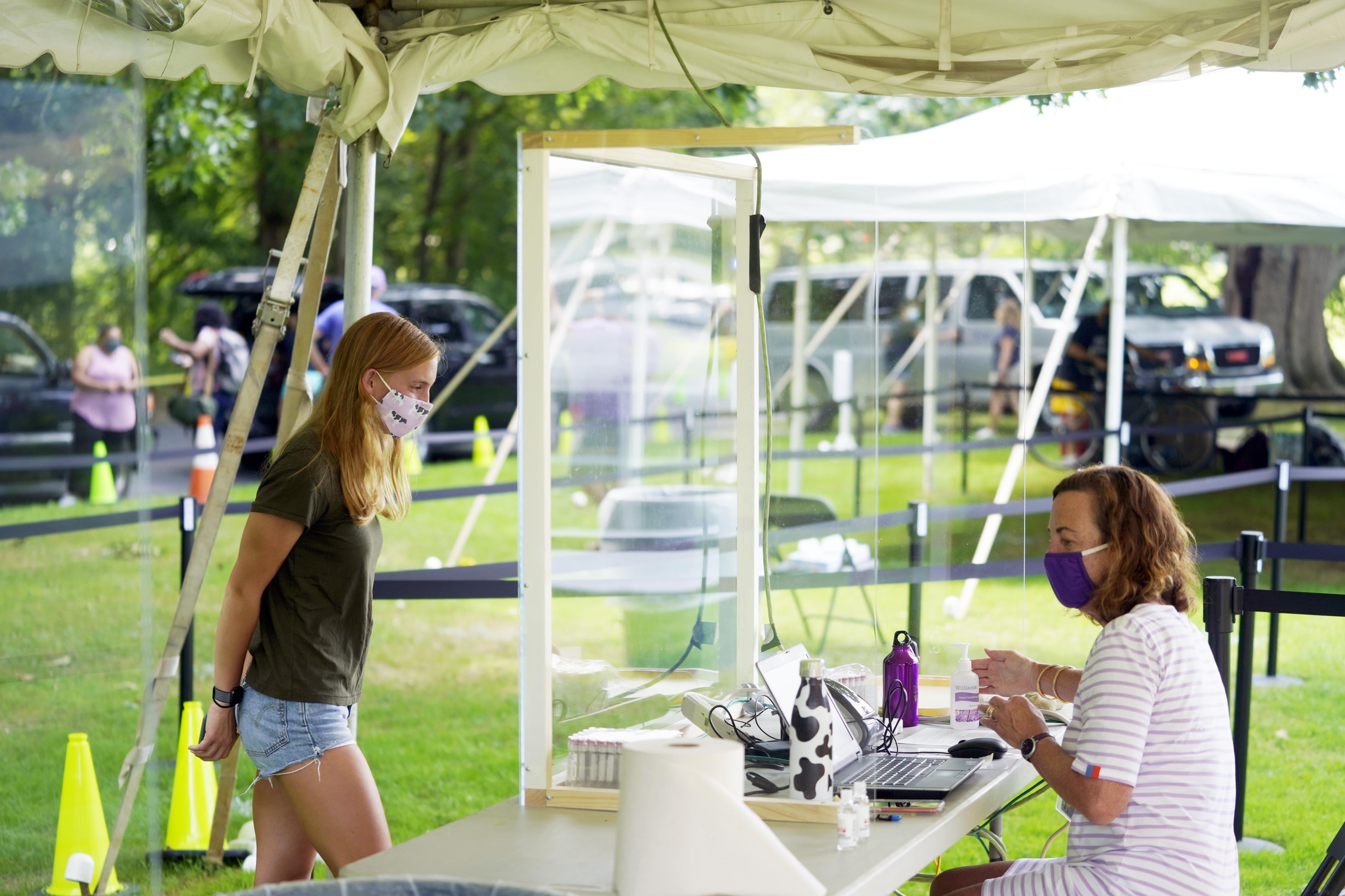 Williams College senior Sarah Tully registers and grabs a test kit during a COVID-19 test before the start of the School year, Williamstown, Mass., Monday, August 24, 2020. Students will be isolated and tested twice before the school year starts under strict hygiene protocols. (Ben Garver/The Berkshire Eagle via AP) [Aug-24-2020]