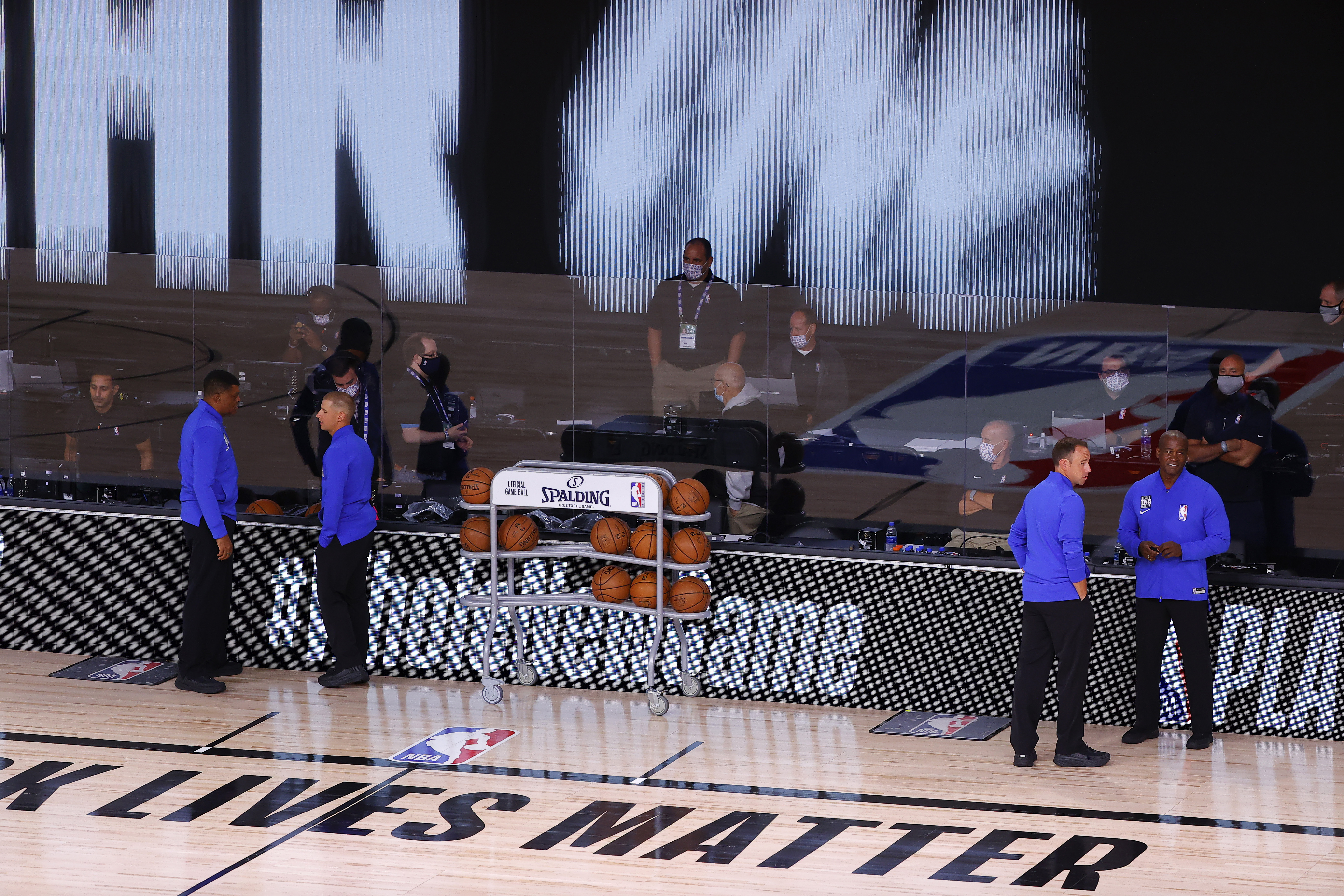Referees stand on an empty court before the start of a scheduled game between the Milwaukee Bucks and the Orlando Magic for Game 5 of an NBA basketball first-round playoff series, Wednesday, Aug. 26, 2020, in Lake Buena Vista, Fla.