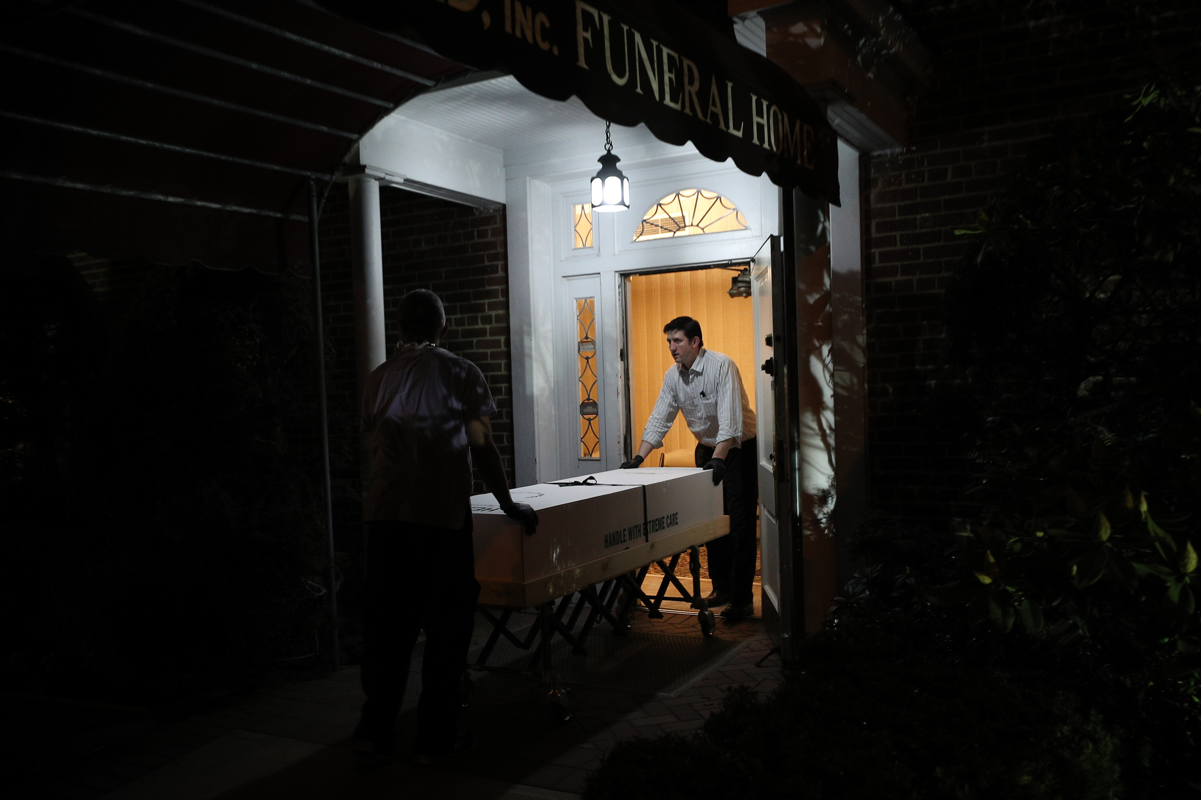 Omar Rodriguez (left) and Joseph Neufeld Jr. (right) carry a casket at the Gerard J. Neufeld funeral home in Queens, New York on April 29, 2020.