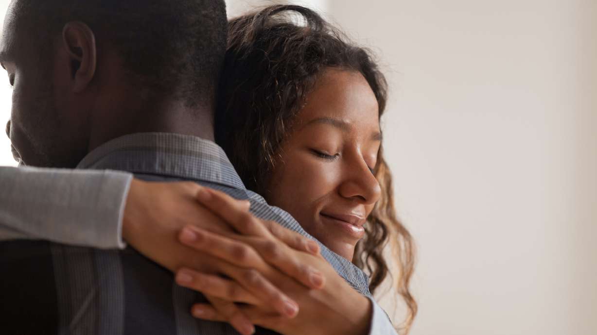 Close up young black american wife embracing husband. Portrait of woman with closed eyes, man rear view. Attractive affectionate couple in love, romantic relationship support and gratefulness concept