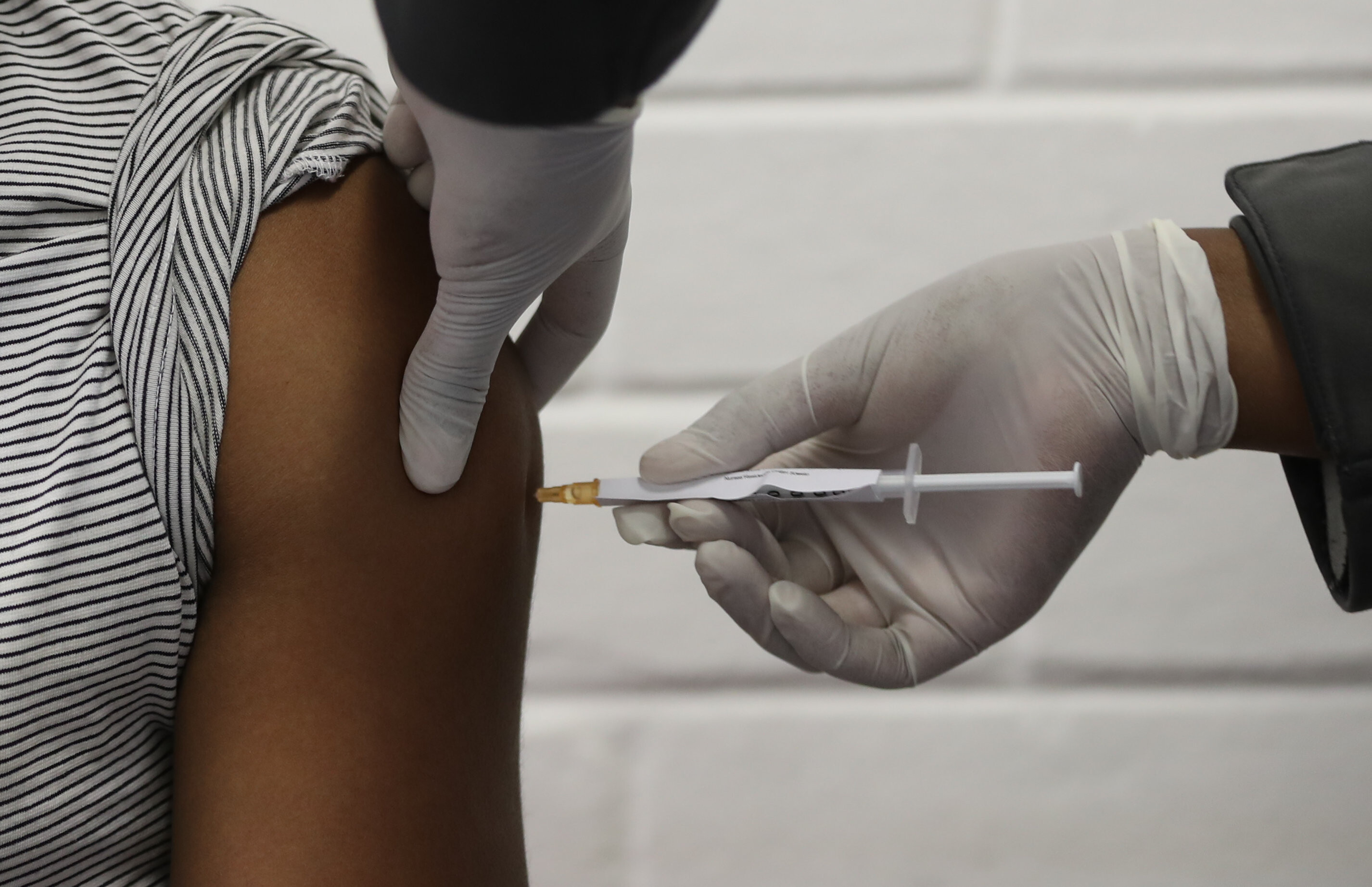 One of the first South African Oxford vaccine trialists looks on as a medical worker injects him with the clinical trial for a potential vaccine against the COVID-19 coronavirus at the Baragwanath hospital in Soweto, South Africa, on June 24 ,2020.