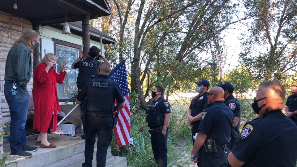 South Salt Lake Police officers replace a woman's flag and pole after she used an old pole to fend off a burglar at her property, breaking the flag in the process, on Monday, August 31, 2020. 