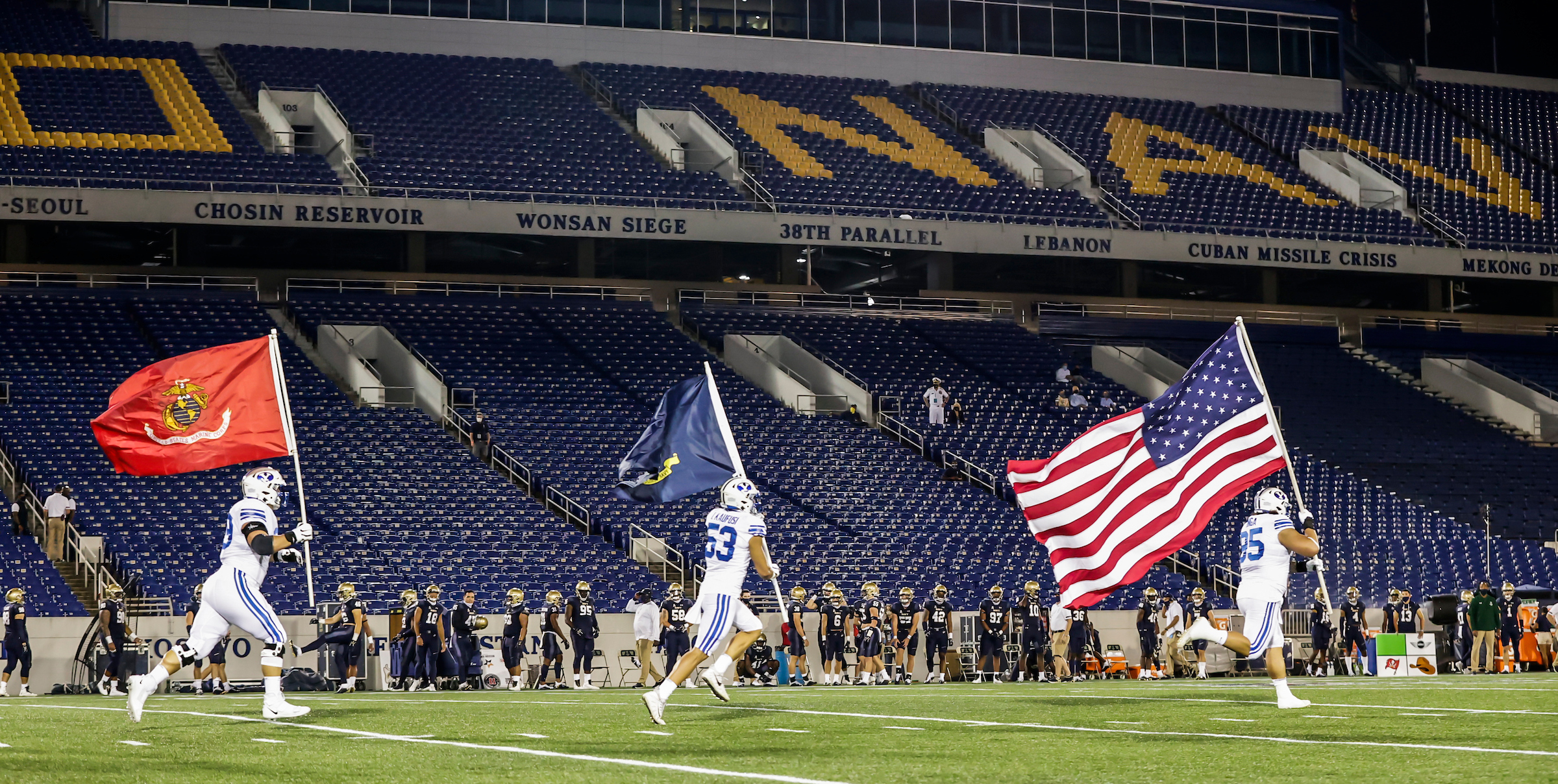 BYU's Tristen Hoge, Isaiah Kaufusi and Khyiris Tonga carry flags onto the field in Annapolis, Maryland before the start of the game against Navy, Monday, Sept. 7, 2020.